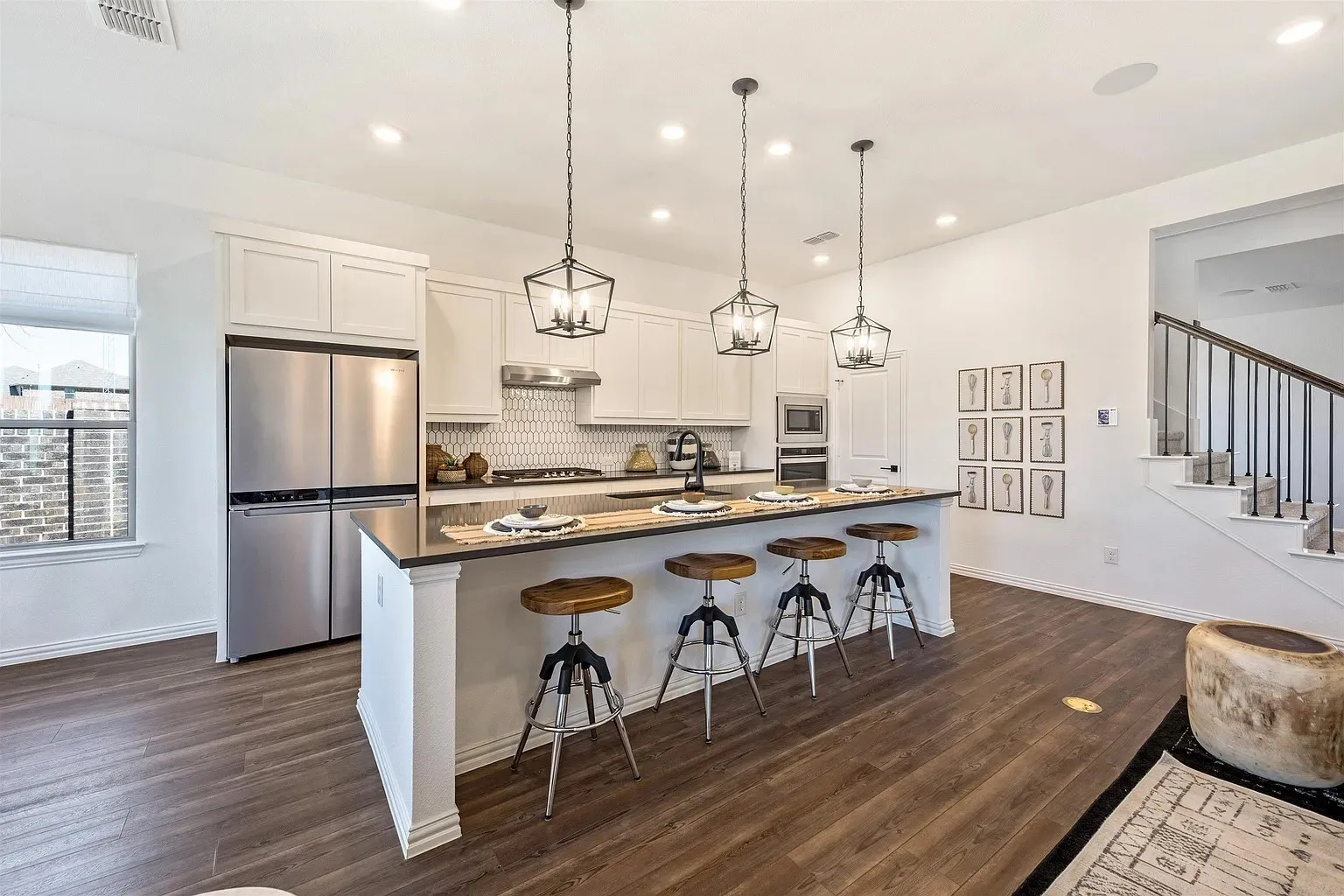 Kitchen with white cabinetry, stainless steel appliances, and wood-finish flooring