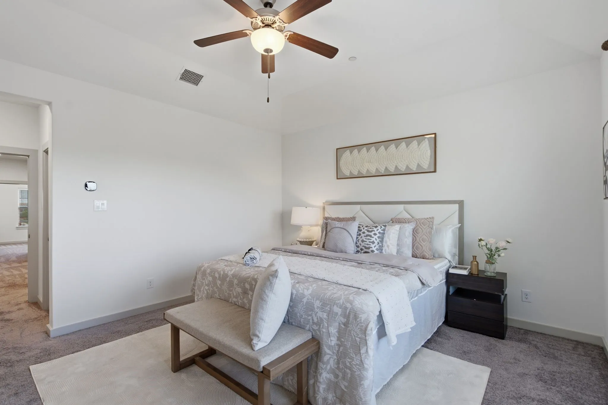 Ceiling fan with light fixture, wall-mounted thermostat, and carpeted flooring