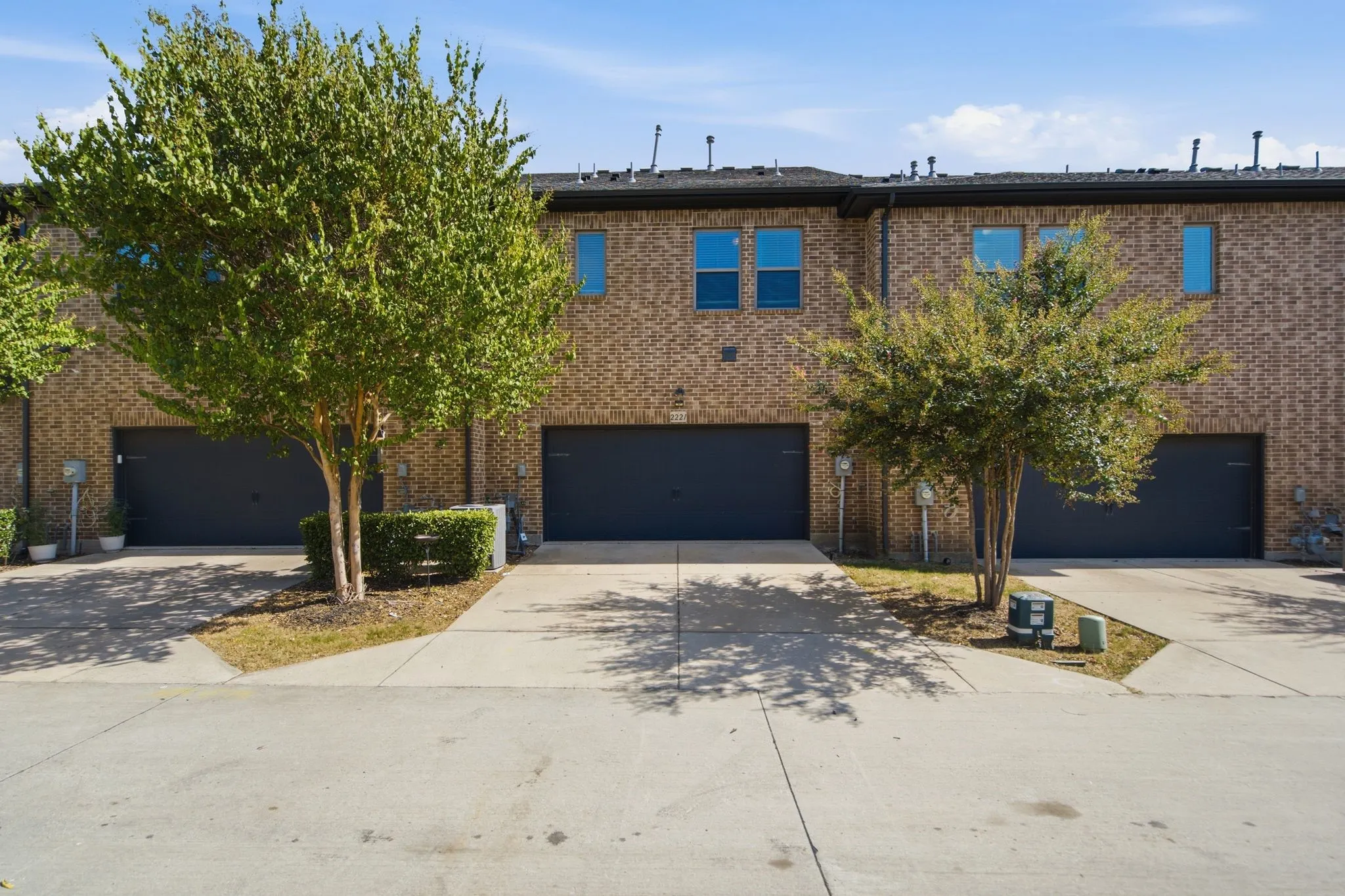 Brick facade townhome with individual garages and concrete driveways