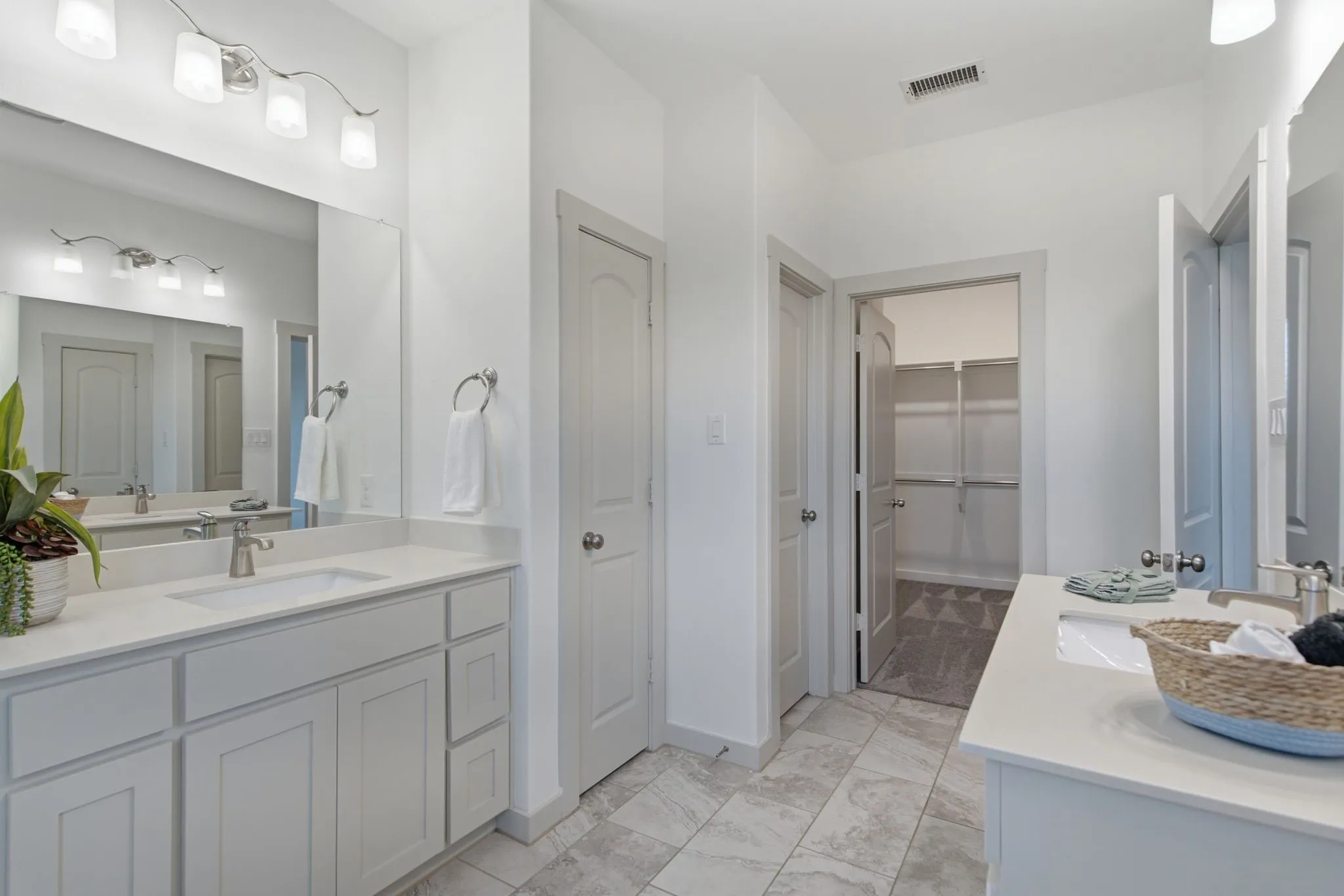 Bathroom featuring a double vanity with light cabinetry and solid surface countertops