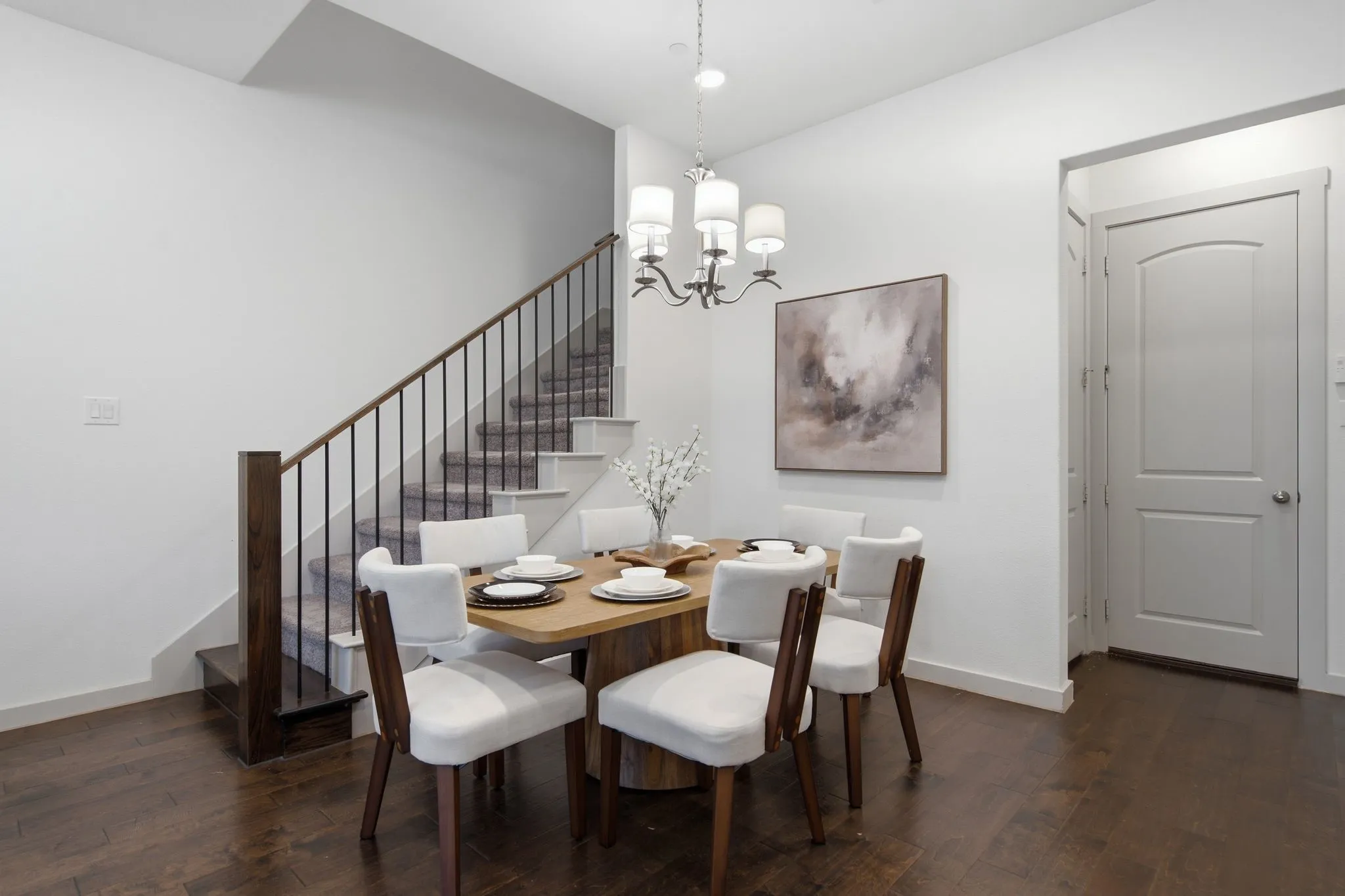 Hardwood flooring extending throughout the space, complemented by a staircase featuring dark wood newel posts and railings with black metal spindles