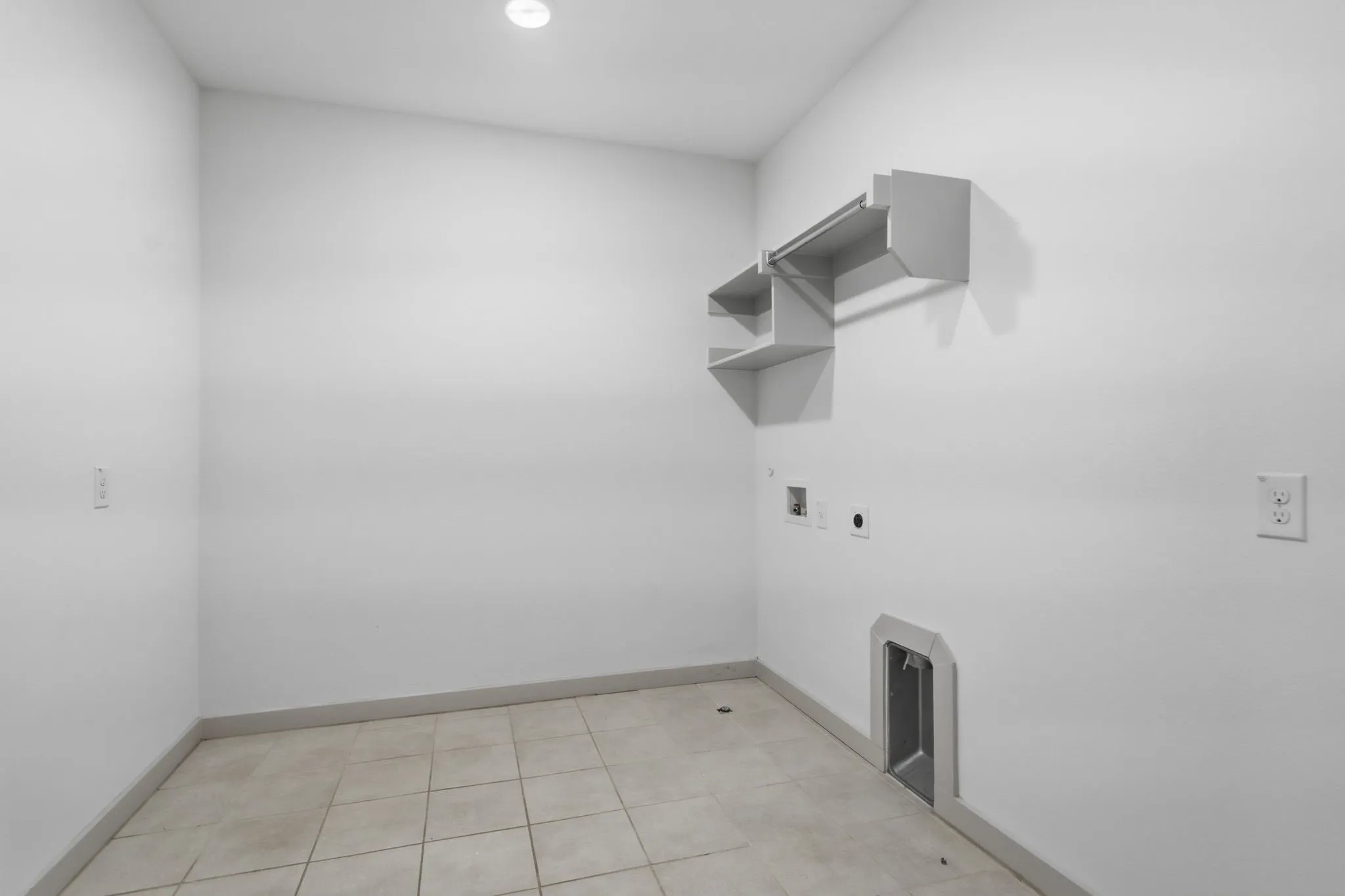 Utility room with tile flooring, built-in shelving, laundry hookups, and a ceiling light fixture
