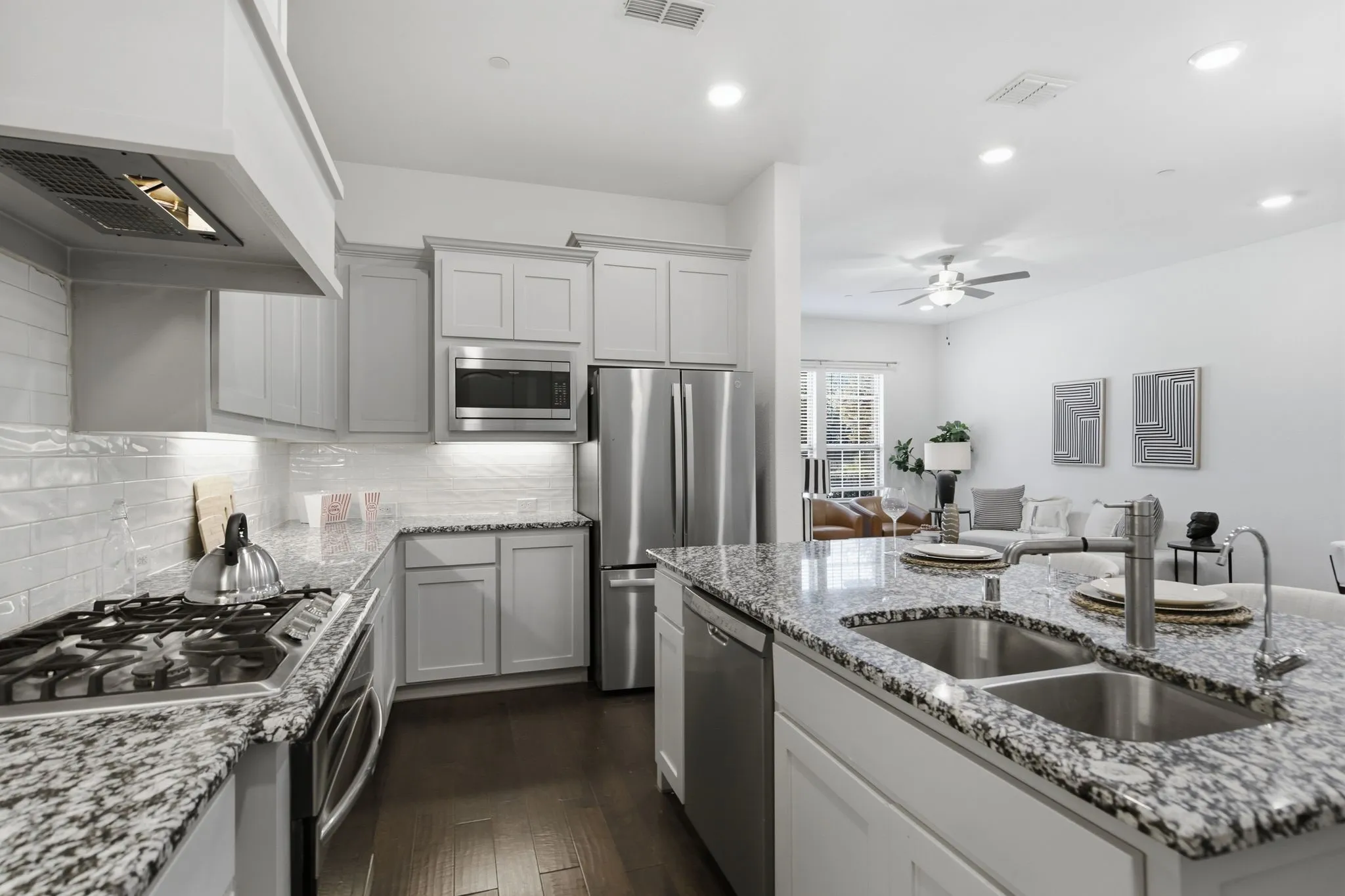 Kitchen featuring light cabinetry, stainless steel appliances, granite countertops, and a subway tile backsplash