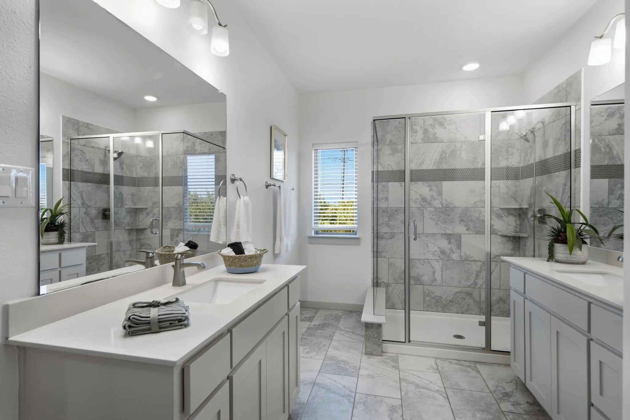 Bathroom featuring a double vanity with stone countertops and undermount sinks, a glass-enclosed shower with tile surround, and tile flooring