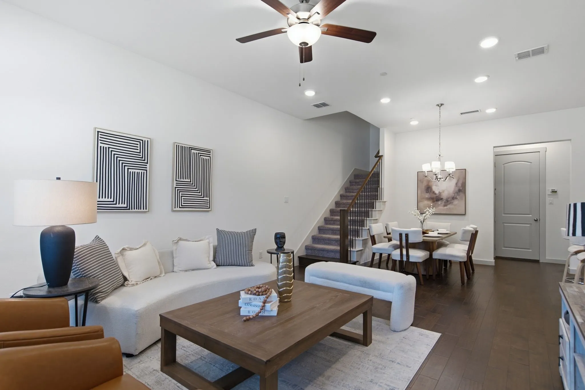 Open-concept living space with dark wood-finish flooring, recessed lighting, a ceiling fan, and a dining area featuring a chandelier