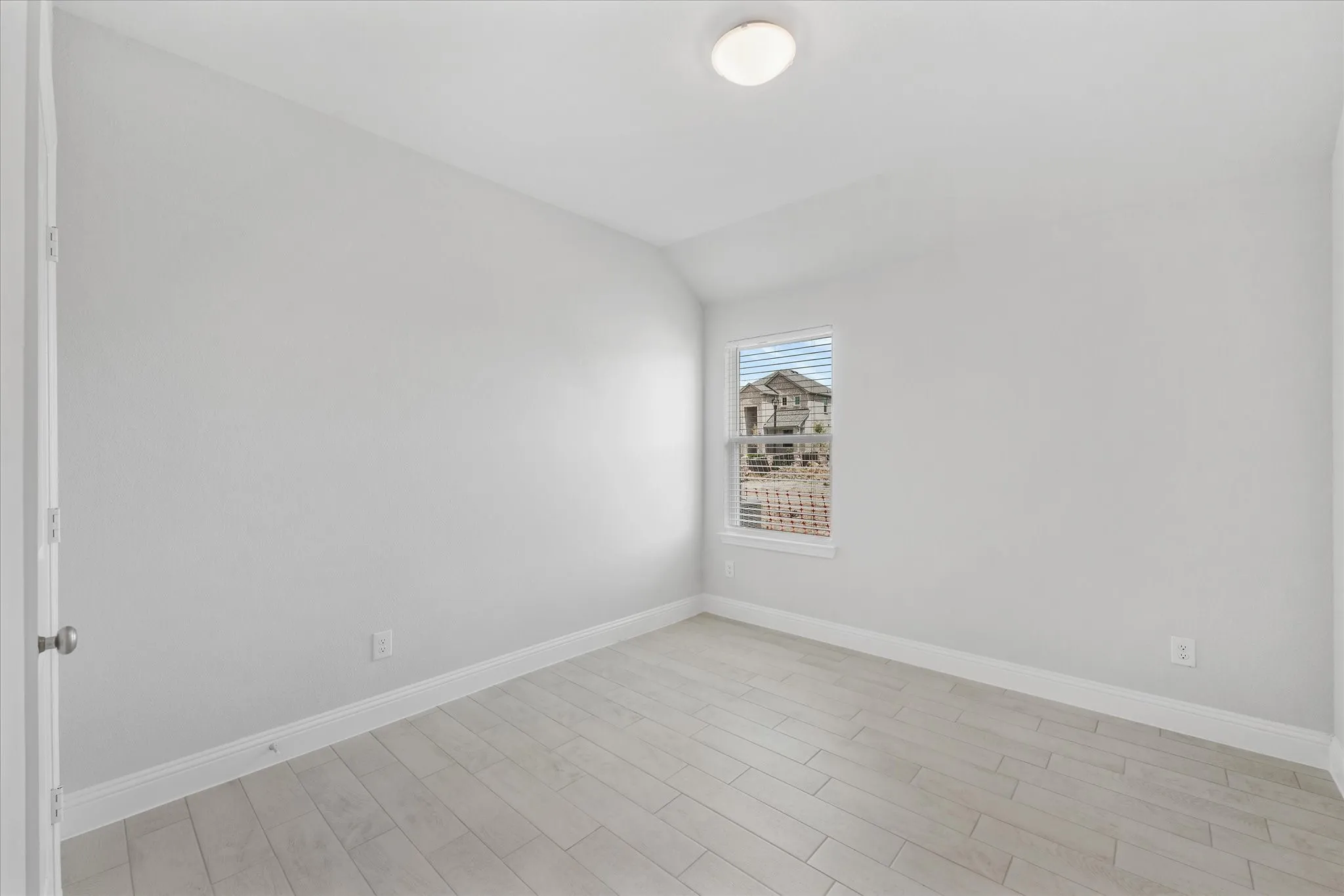 Empty room with light wood-type flooring and lofted ceiling
