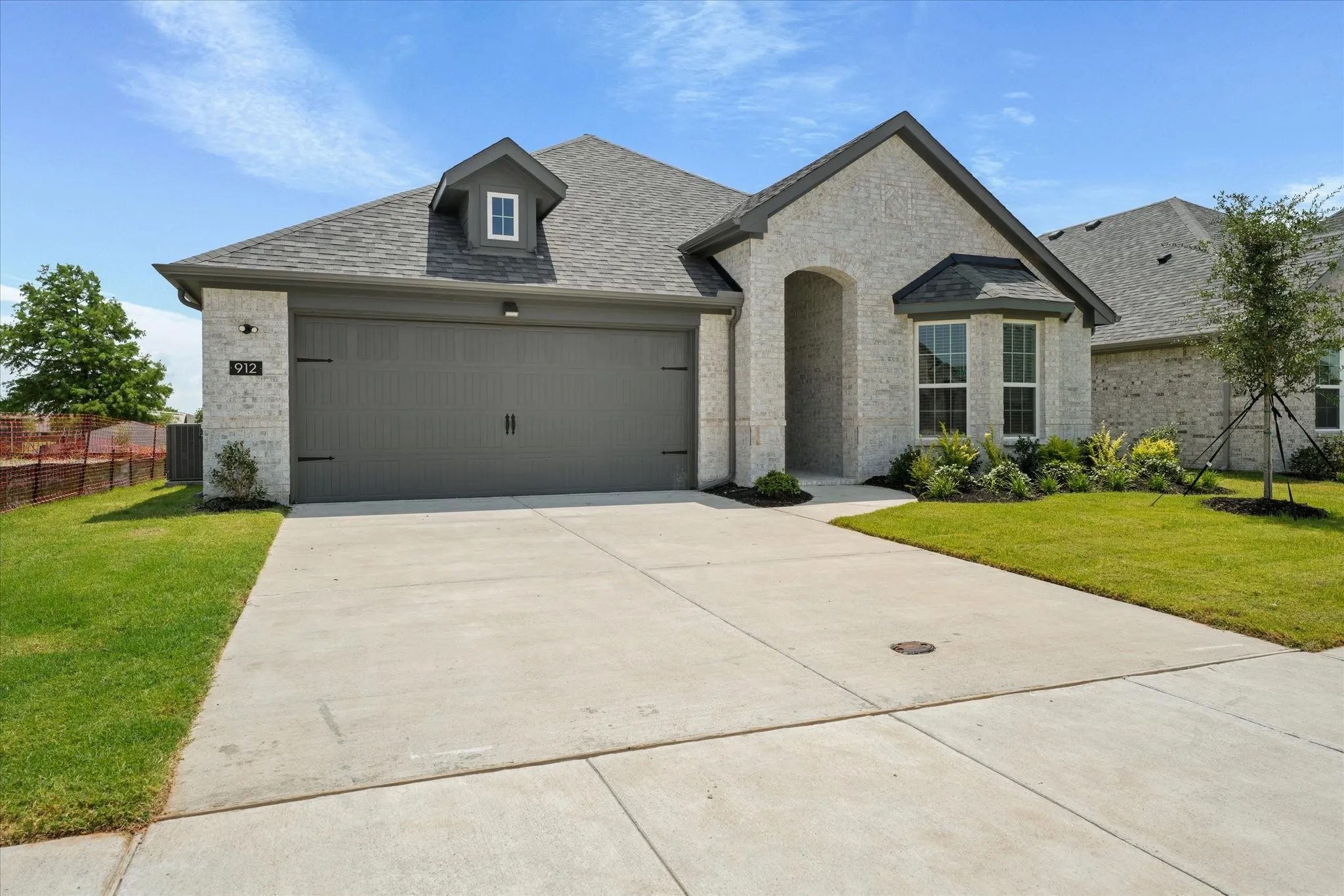 French country home with cooling unit, a garage, and a front lawn