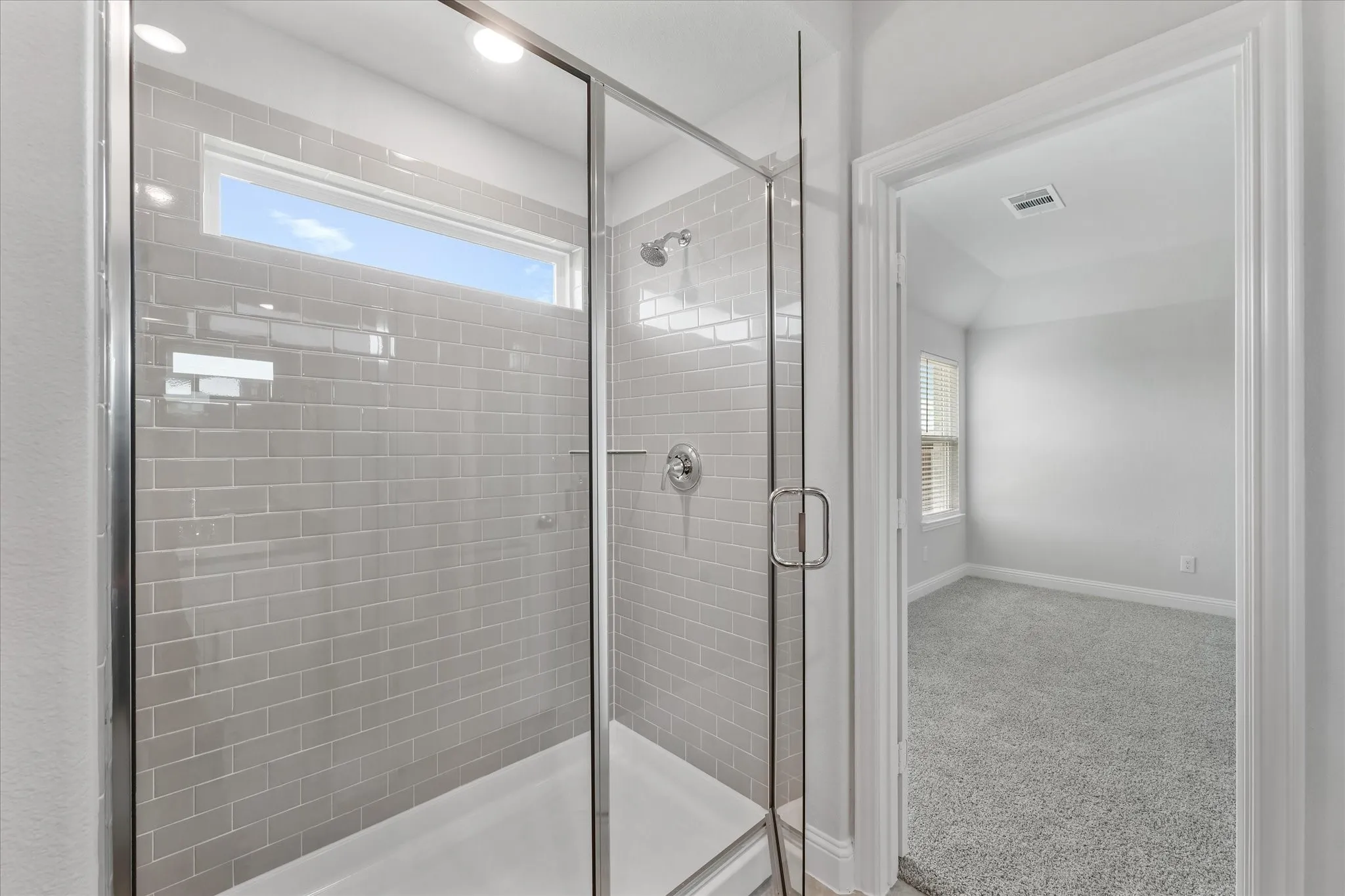 Bathroom featuring a shower with shower door and plenty of natural light