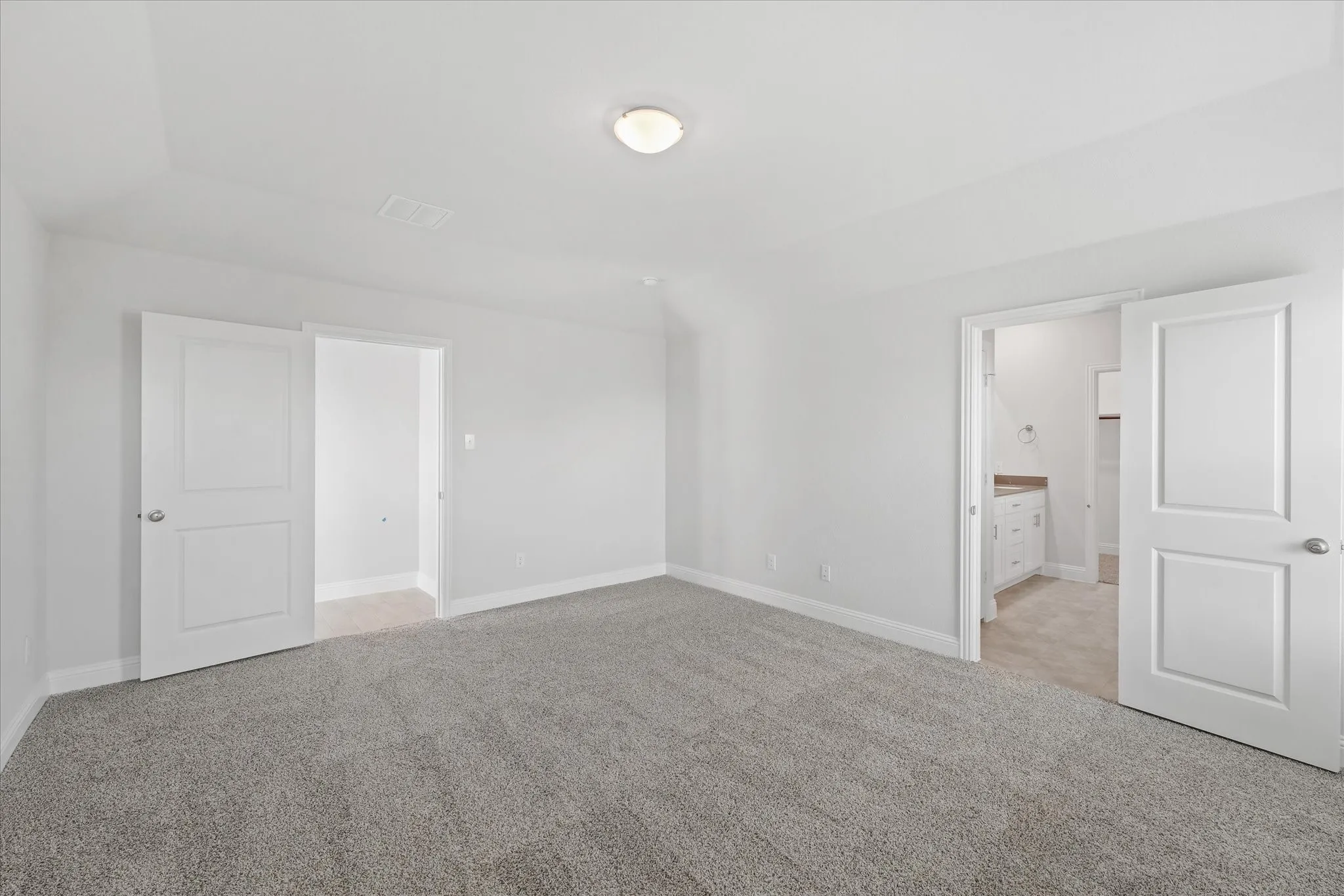 Unfurnished bedroom with light carpet and ensuite bath
