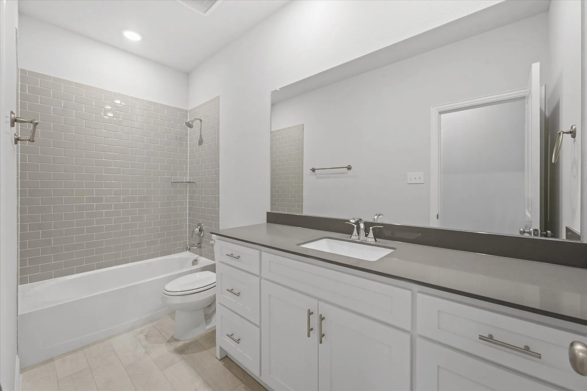 Full bathroom featuring vanity, tile patterned flooring, tiled shower / bath, and toilet