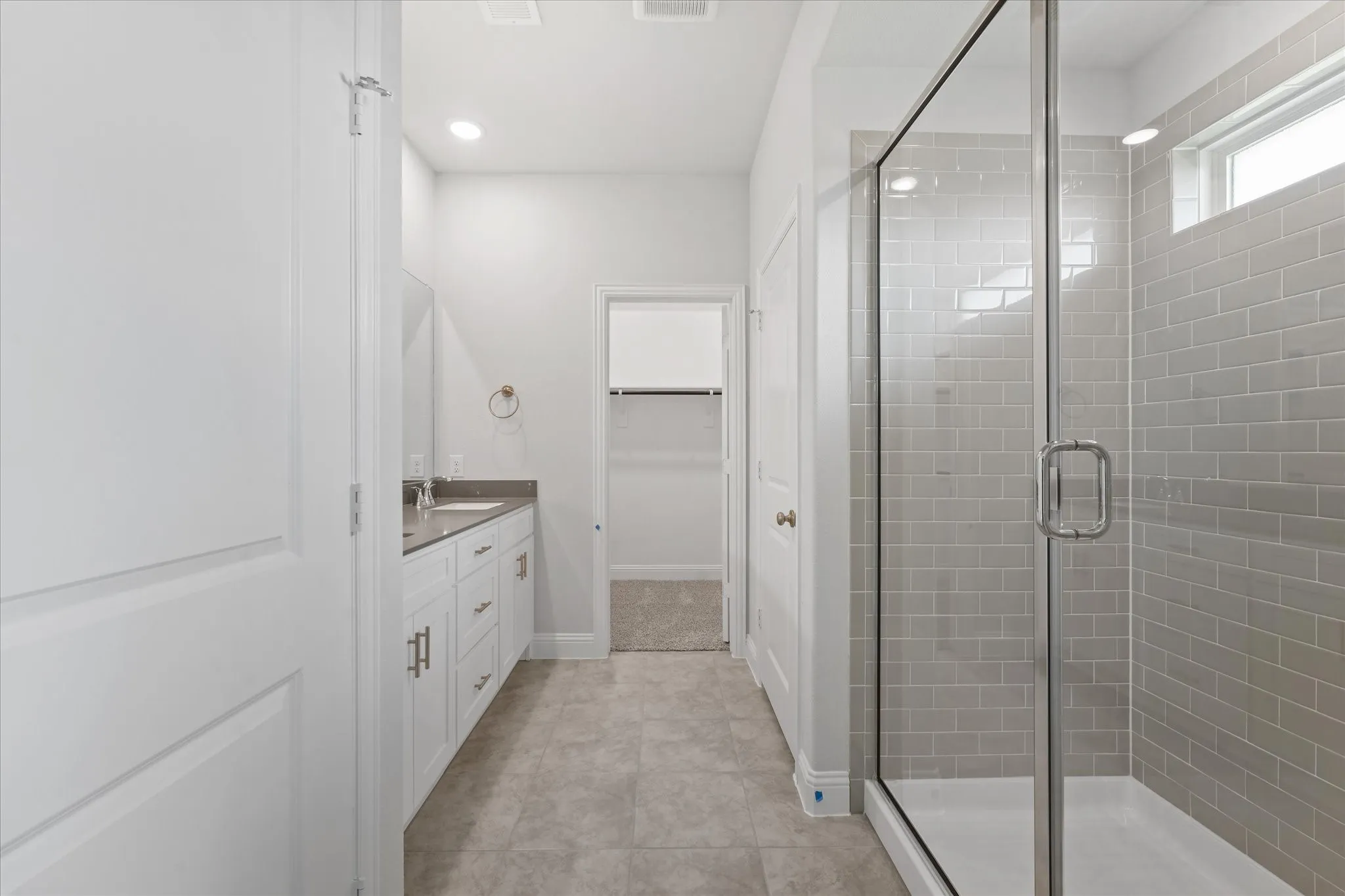 Bathroom with a shower with shower door, vanity, and tile patterned flooring