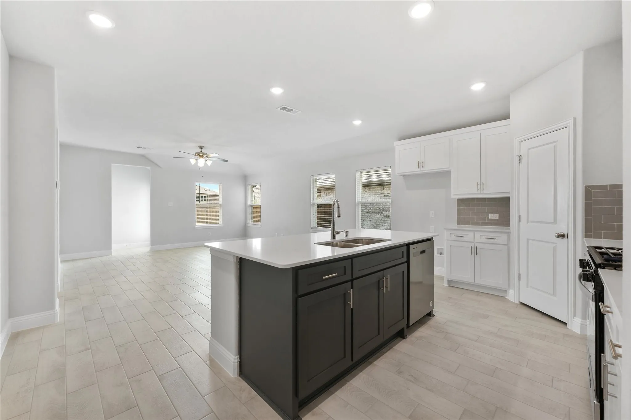 Kitchen featuring stainless steel appliances, sink, decorative backsplash, a kitchen island with sink, and ceiling fan