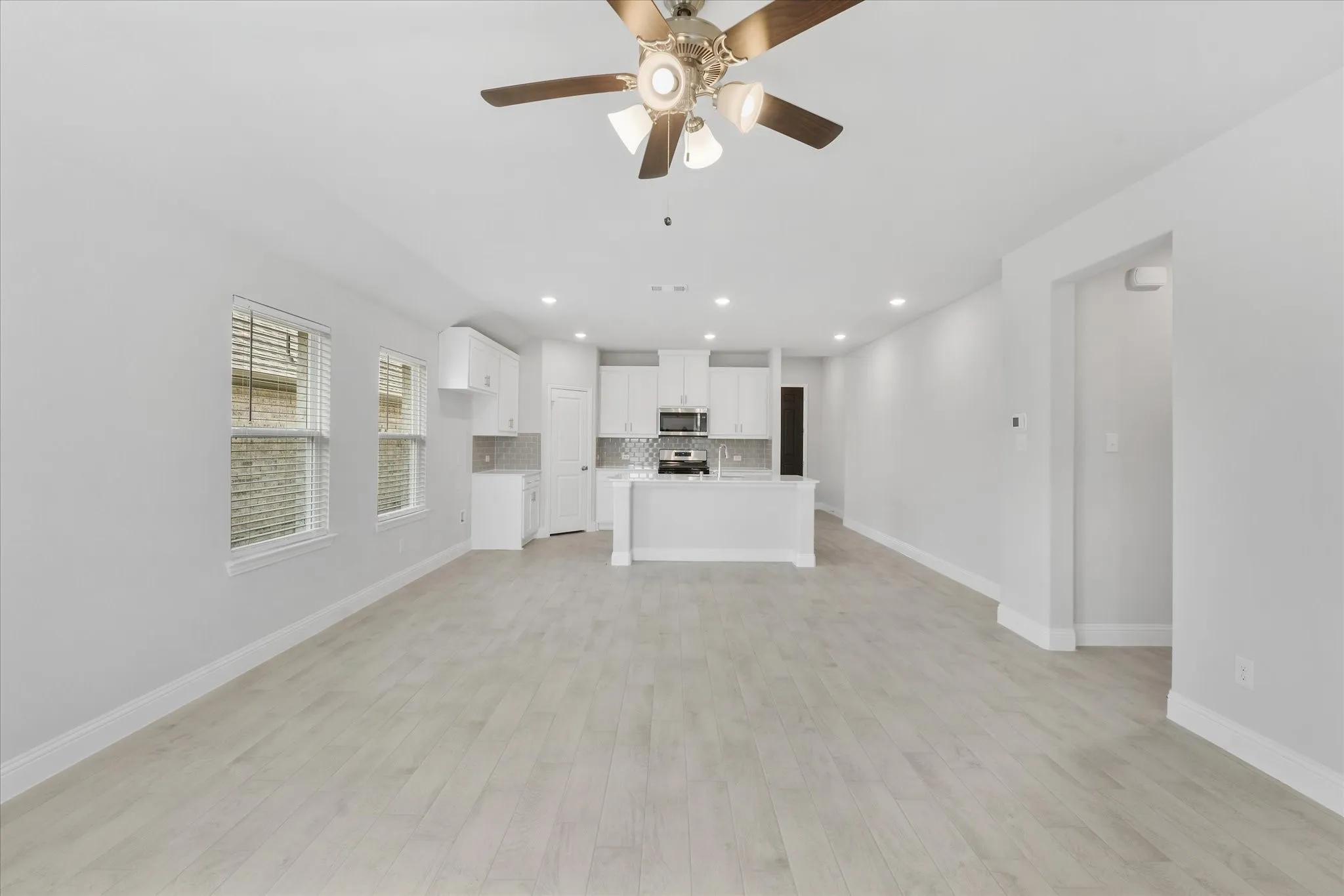 Unfurnished living room featuring light wood-type flooring and ceiling fan