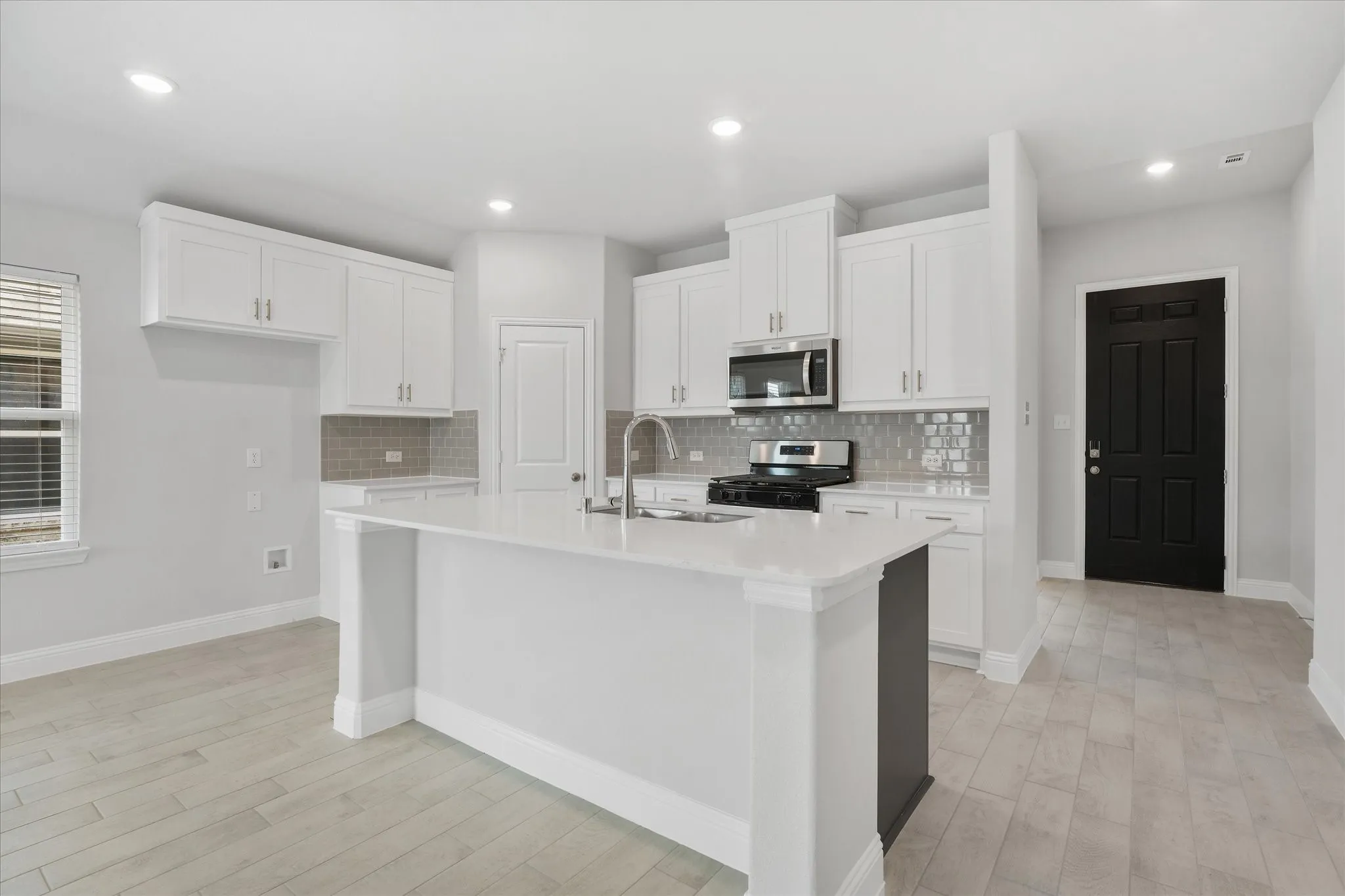 Kitchen with a kitchen island with sink, range with gas cooktop, and white cabinets