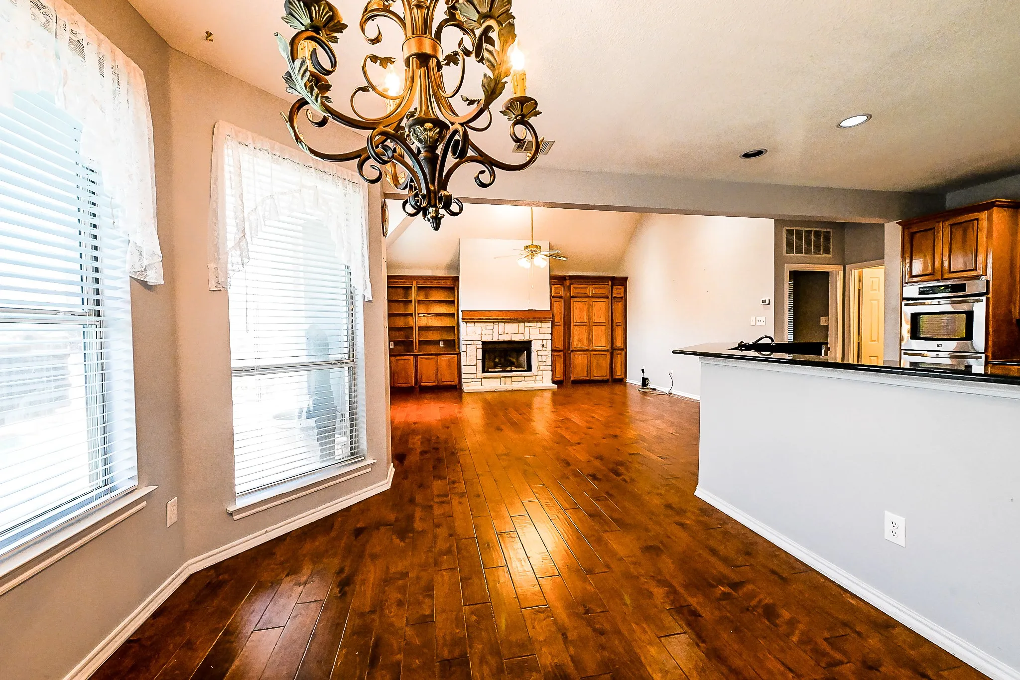 Wood-finish flooring, recessed lighting, built-in cabinetry, and a stone-surround fireplace