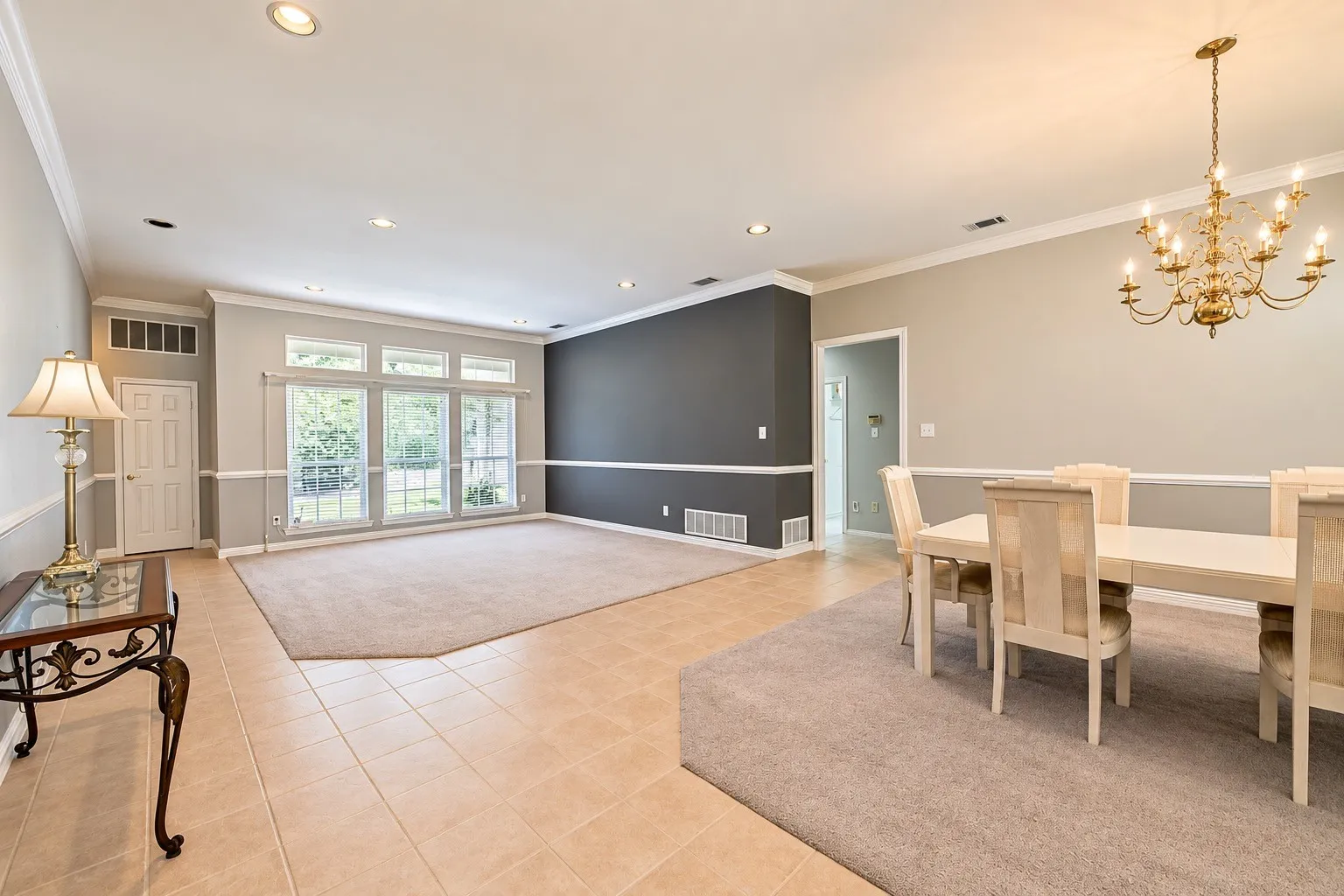 Expansive living area with large windows, recessed lighting, crown molding, and contrasting wall accents