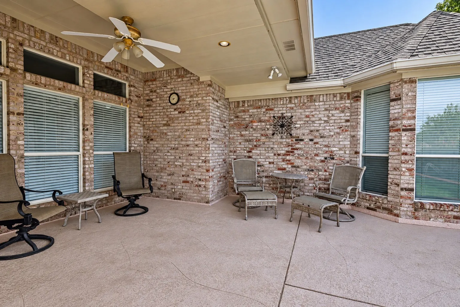Covered patio with brick exterior, textured concrete flooring, recessed lighting, and a ceiling fan