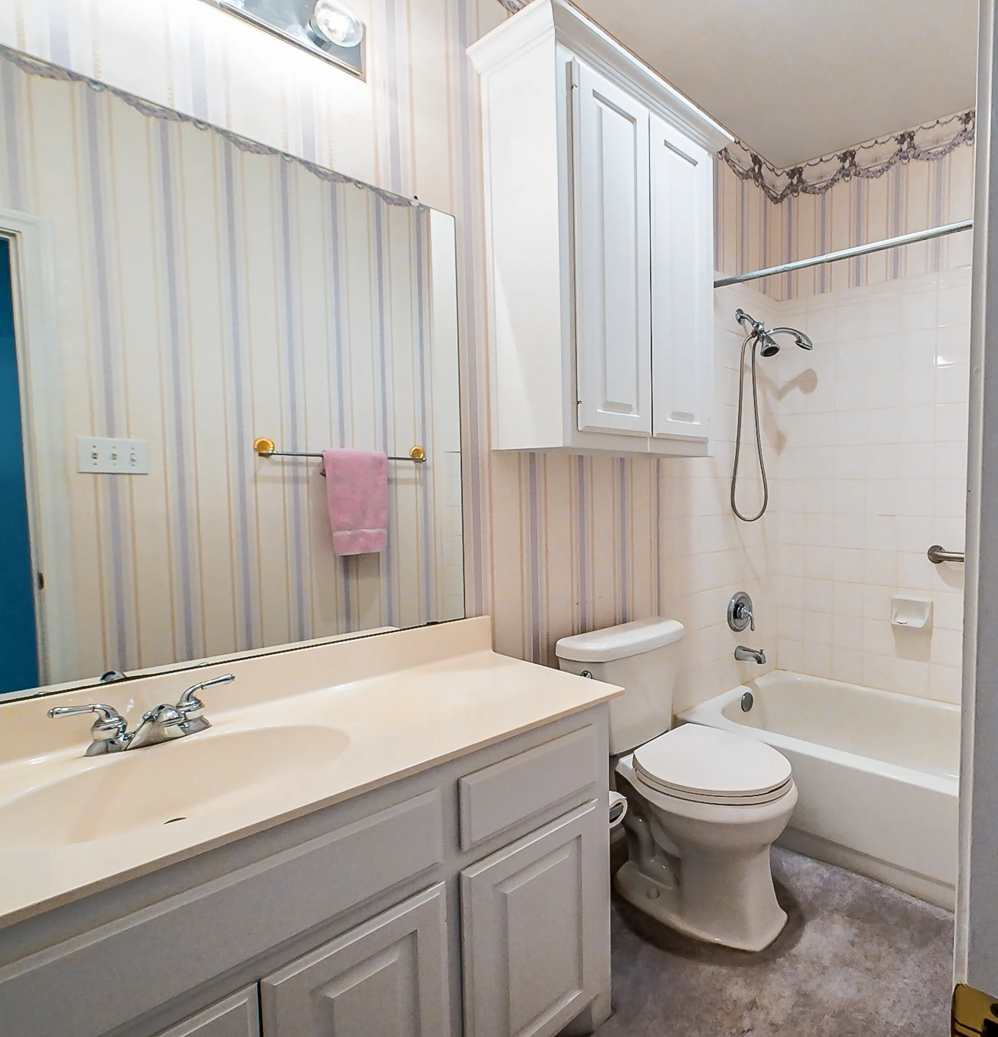Bathroom featuring a single vanity with an integrated sink, white cabinetry, a full-width mirror, a toilet, and a combination tub/shower