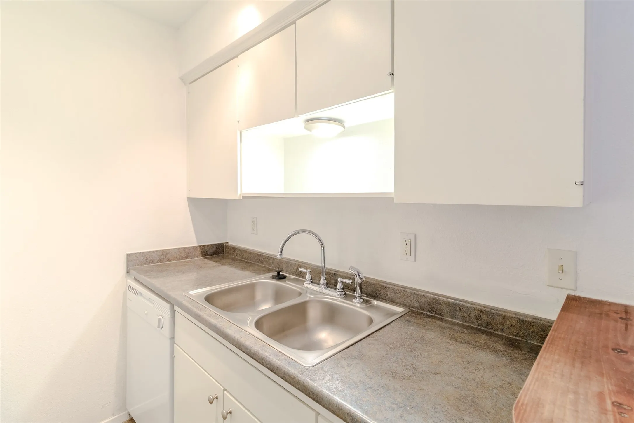 Kitchen featuring white dishwasher and white cabinets