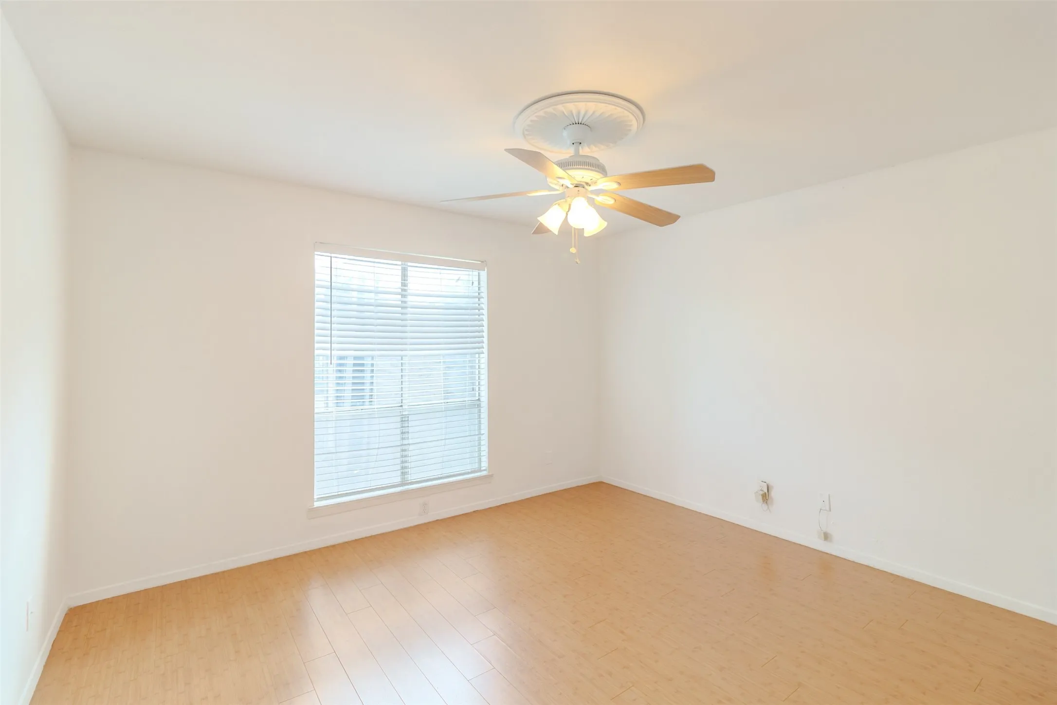 Empty room featuring light wood-type flooring and ceiling fan