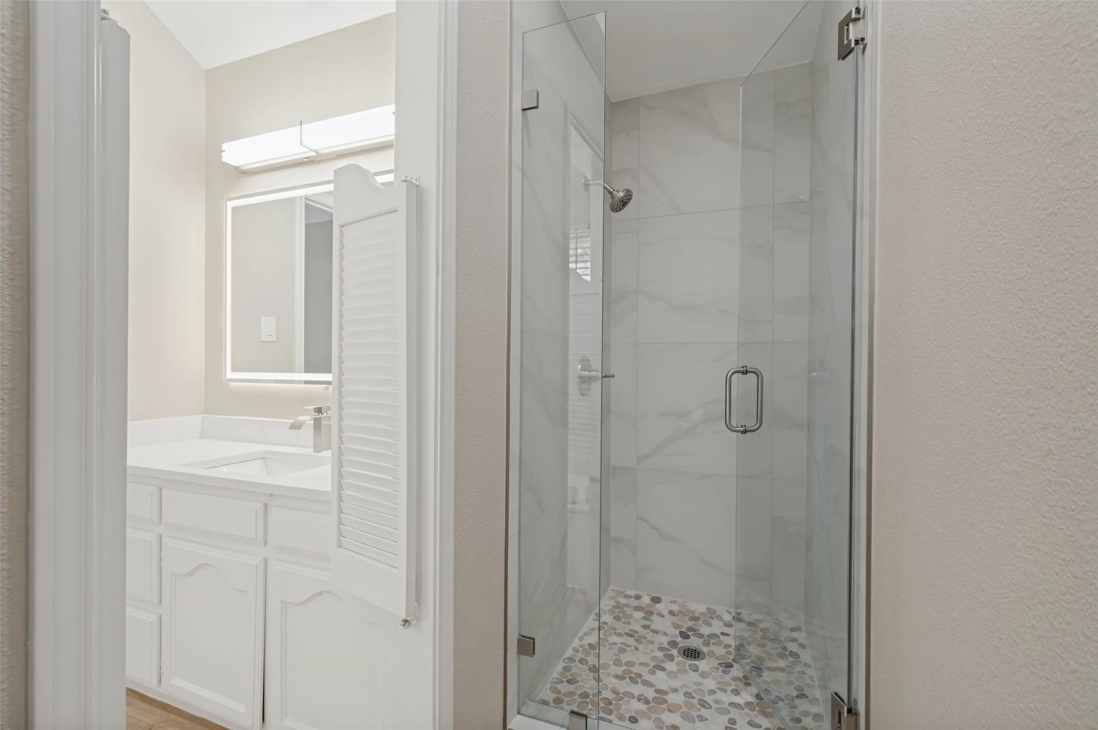 Shower with clear glass enclosure and pebble tile floor