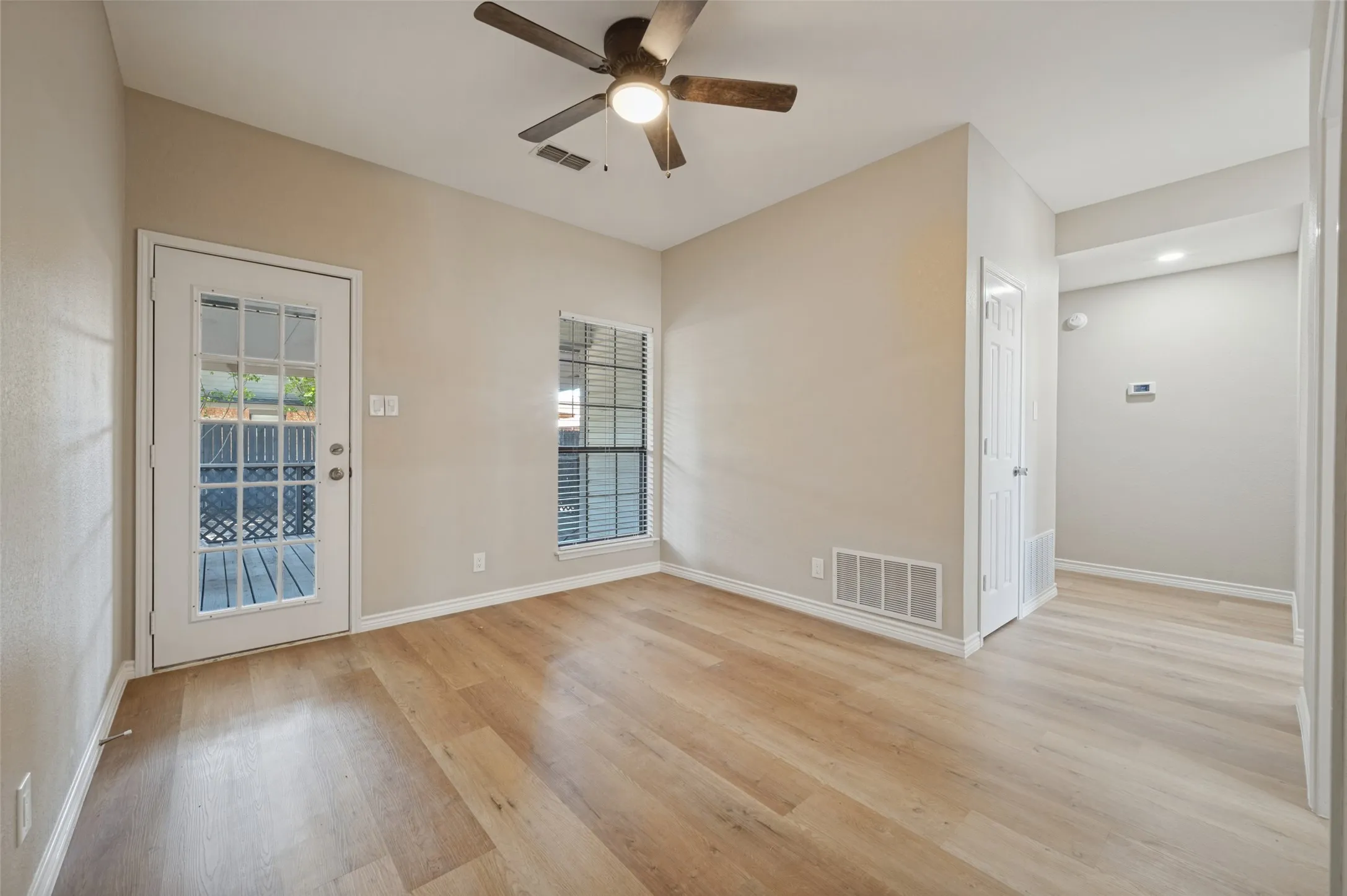 LVP  flooring, ceiling fan, white trim, glass-paneled door, and window with blinds