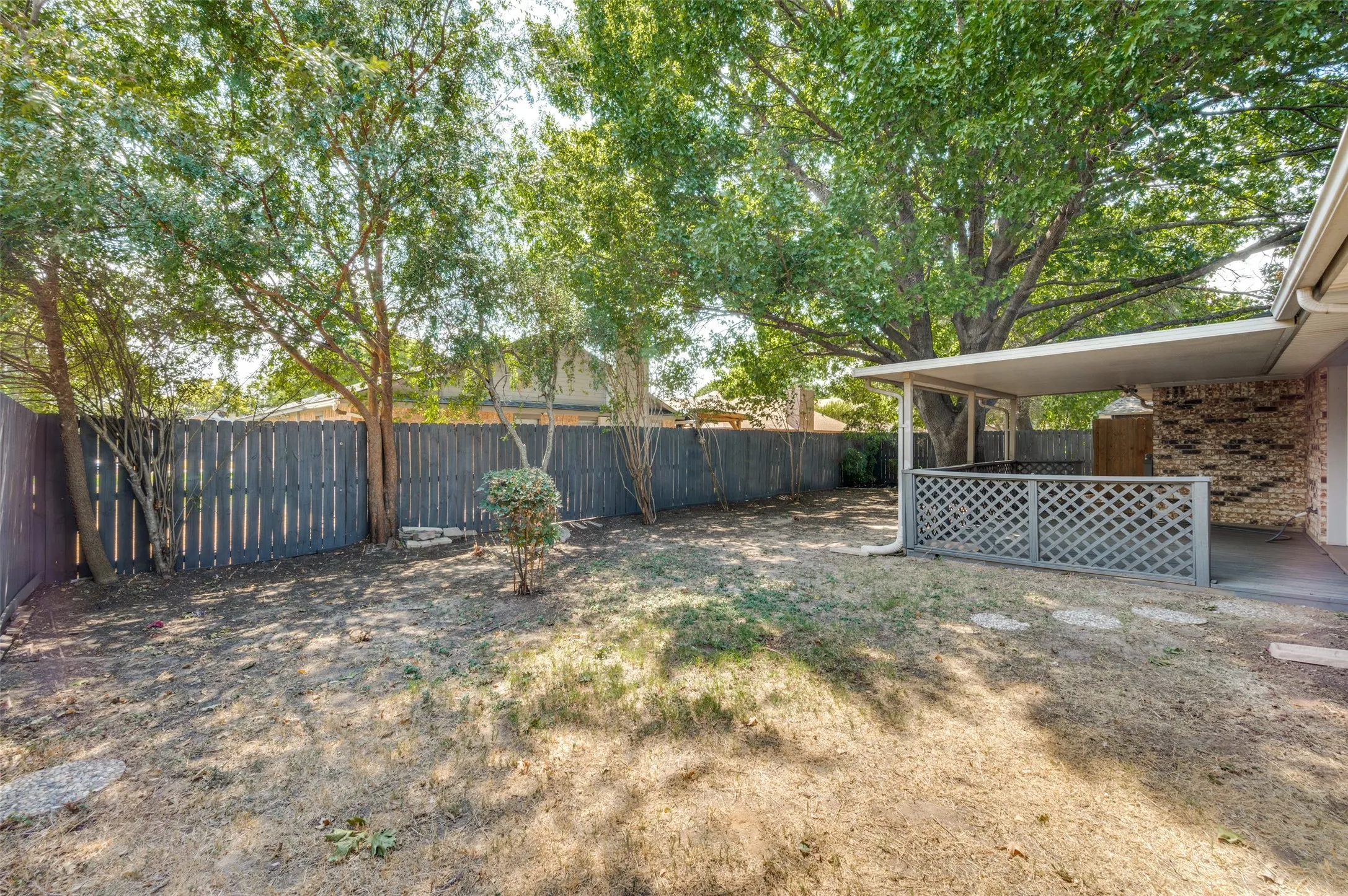  Patio area with a covered deck, lattice detailing, and a privacy fence