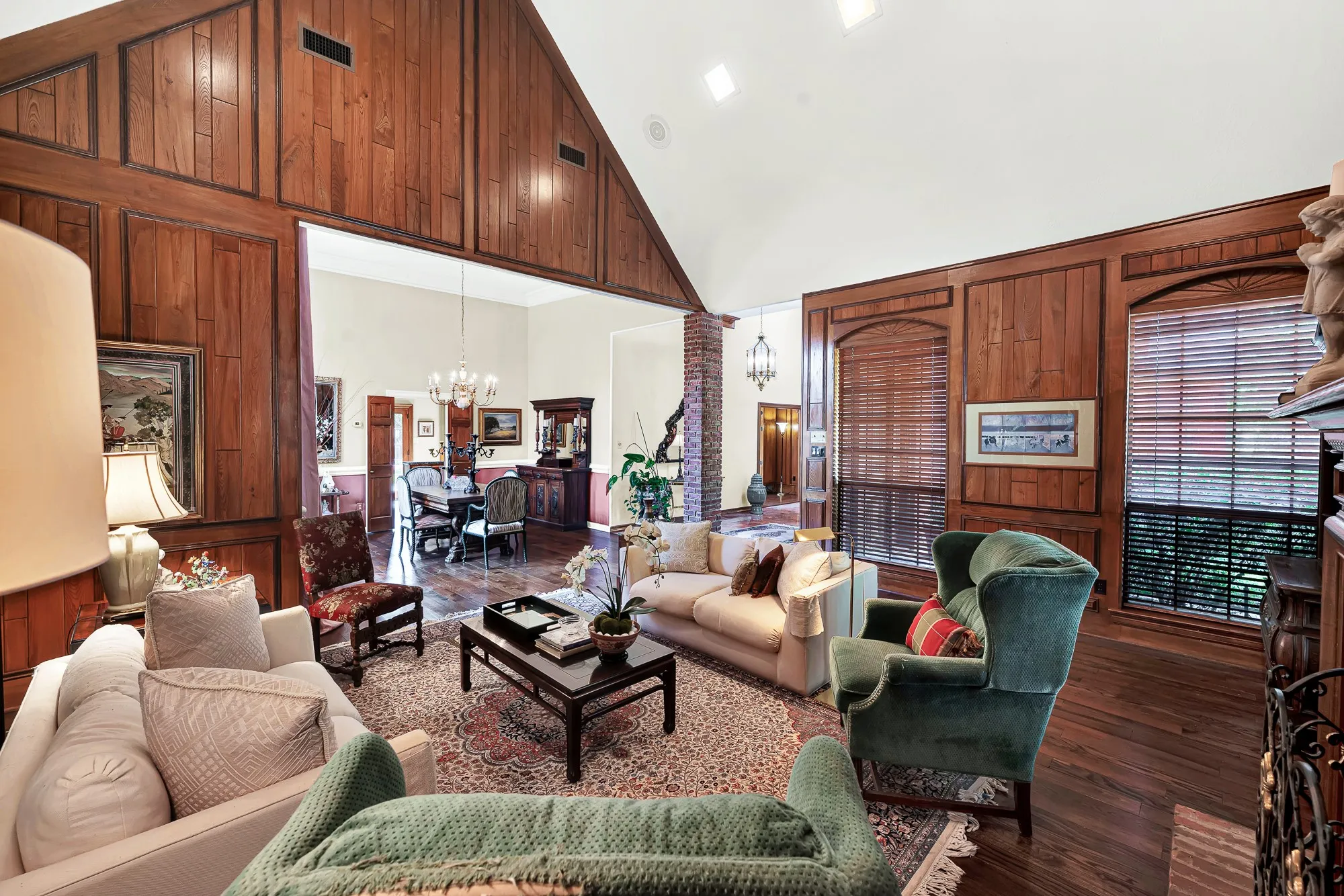 Sophisticated living room featuring rich wood-paneled walls, warm hardwood floors, and an inviting open sightline into the beautifully appointed formal dining room.