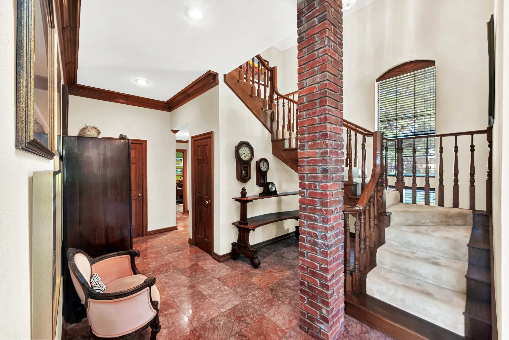 Striking two-story entry with an exposed brick column and richly detailed wood staircase.