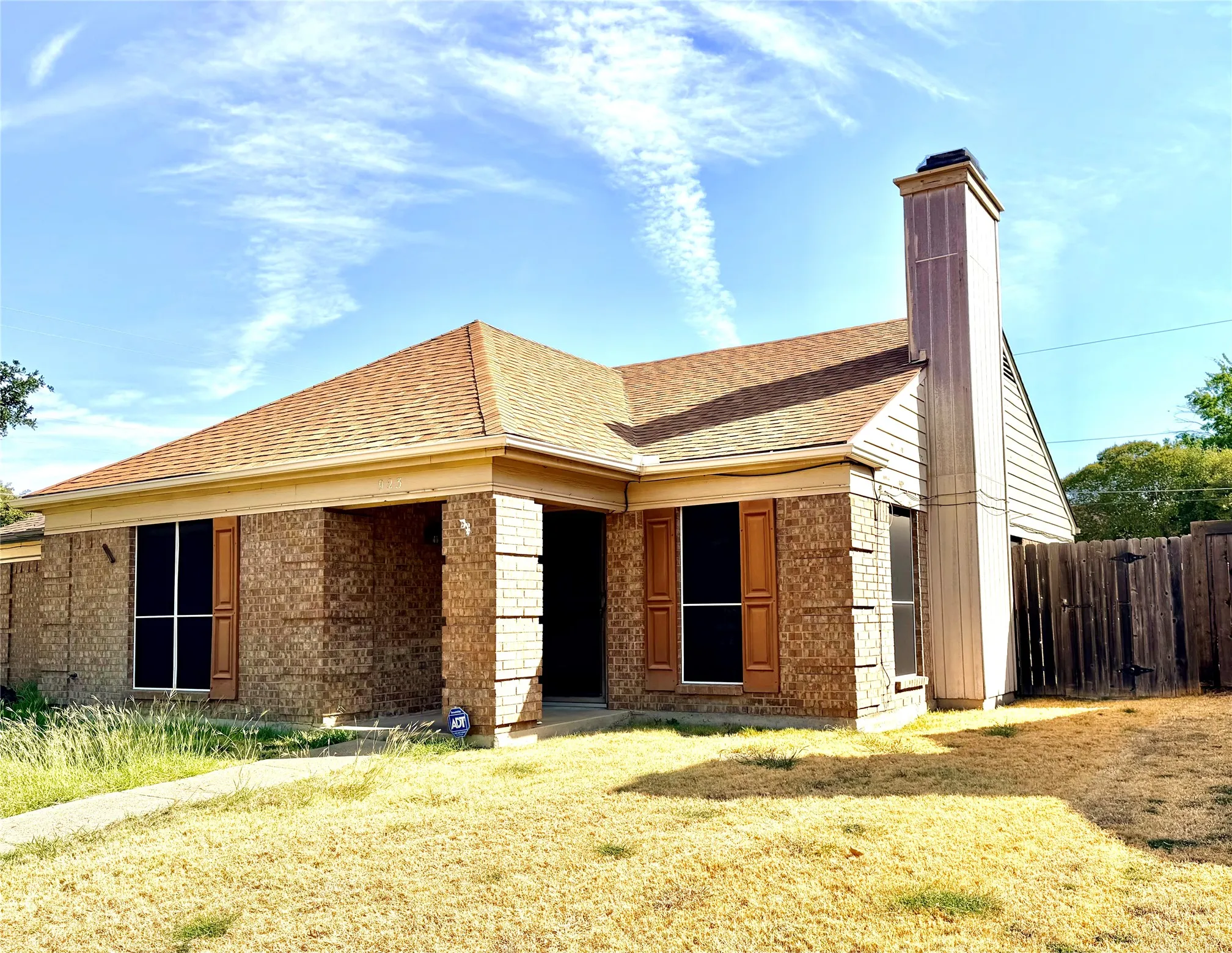 Brick exterior with wood shutters, covered entry, and a prominent chimney feature