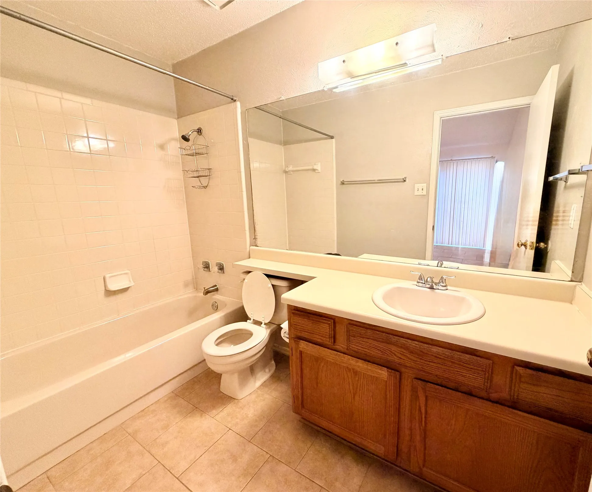 Full vanity mirror with integrated lighting, wood-finish cabinetry, and a tile-surround bathtub