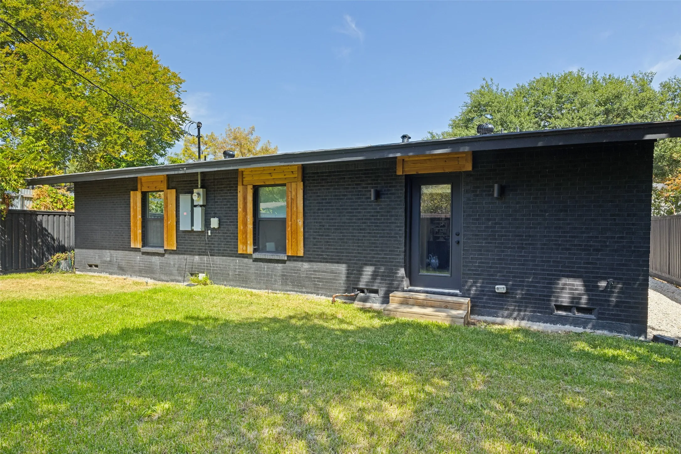 Black brick exterior with wood window surrounds and a flat roofline