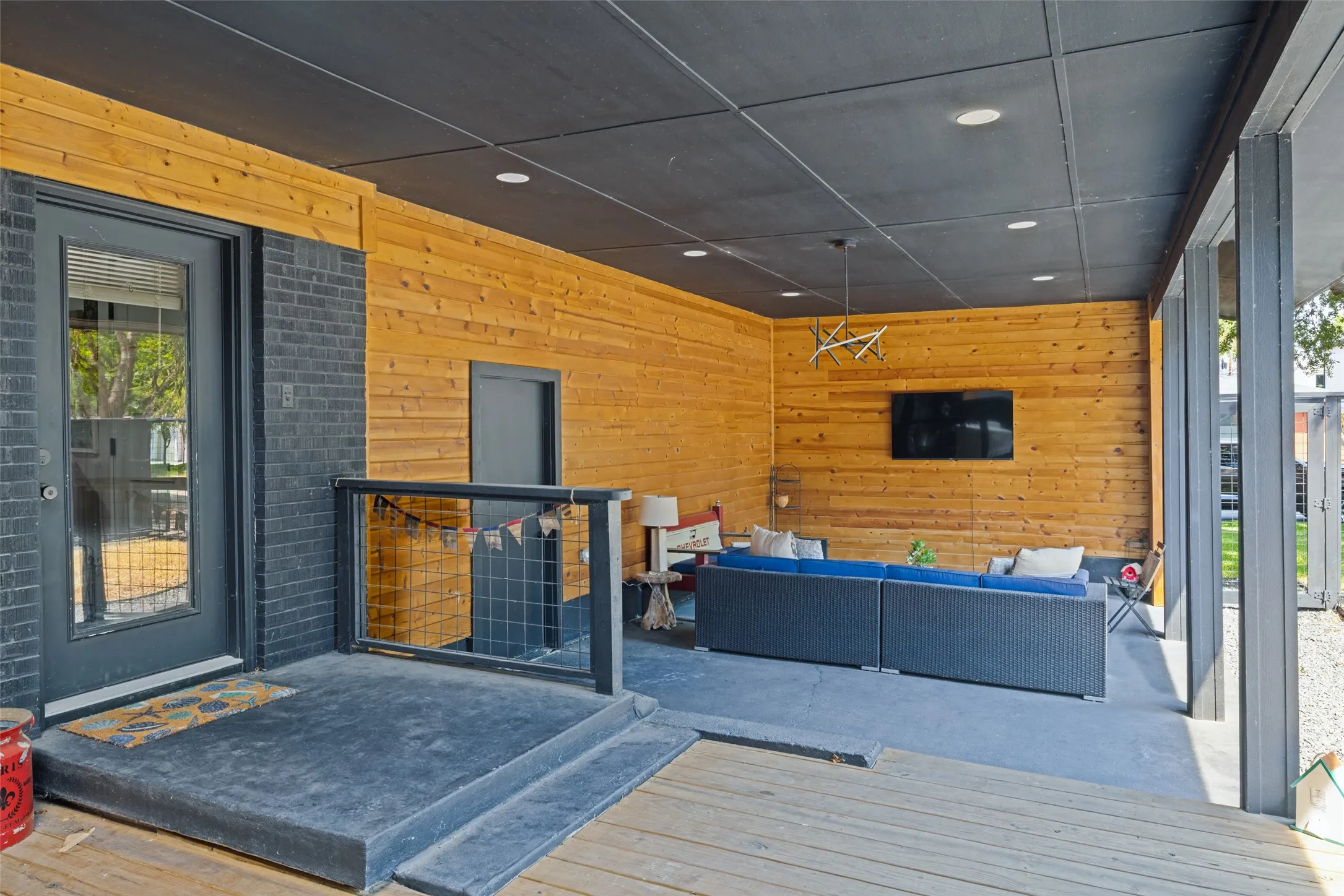 Covered patio with wood-paneled walls, a dark ceiling, recessed lighting, and a modern chandelier