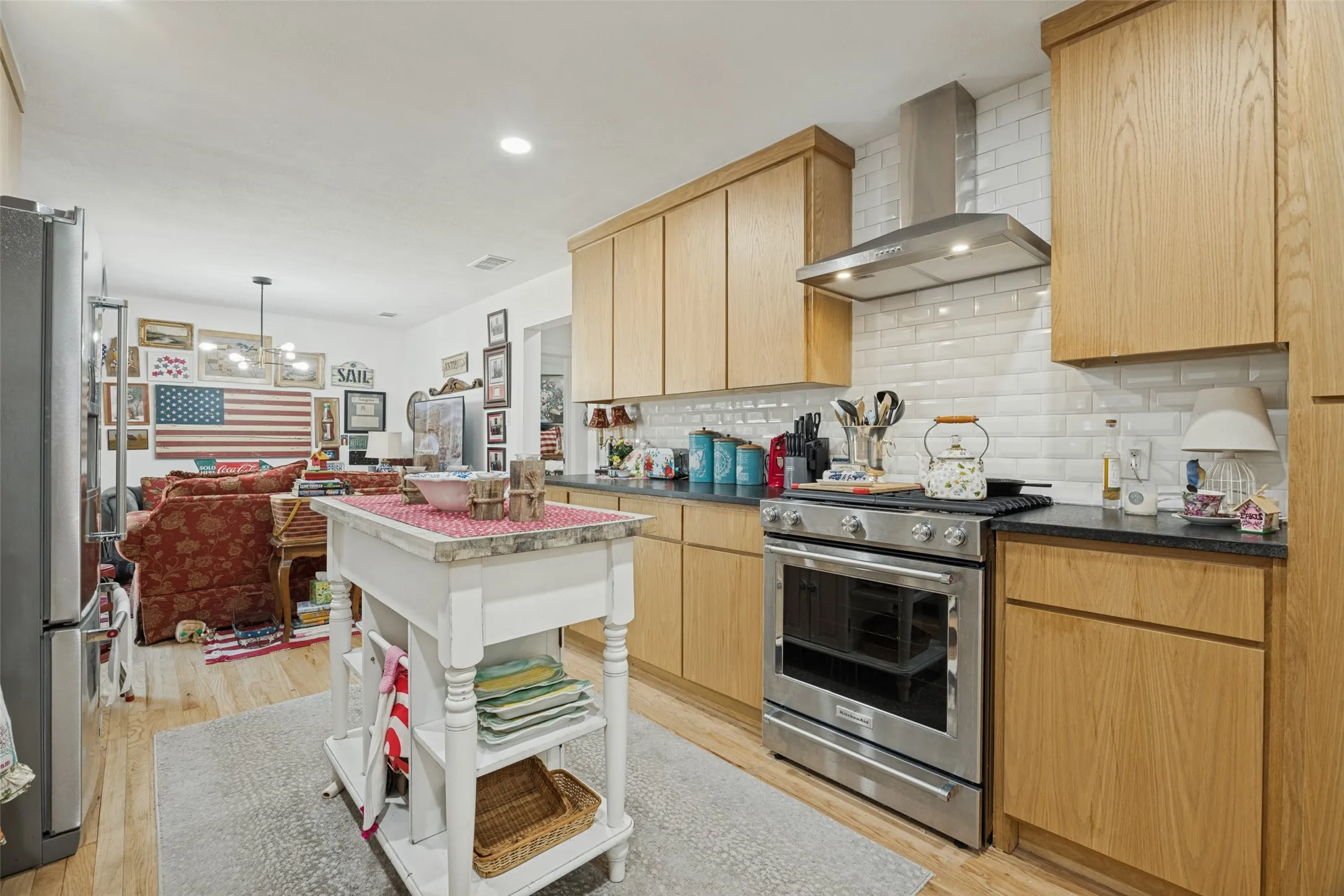 Kitchen featuring wood-finish cabinetry, subway tile backsplash, stainless steel appliances, and dark countertops