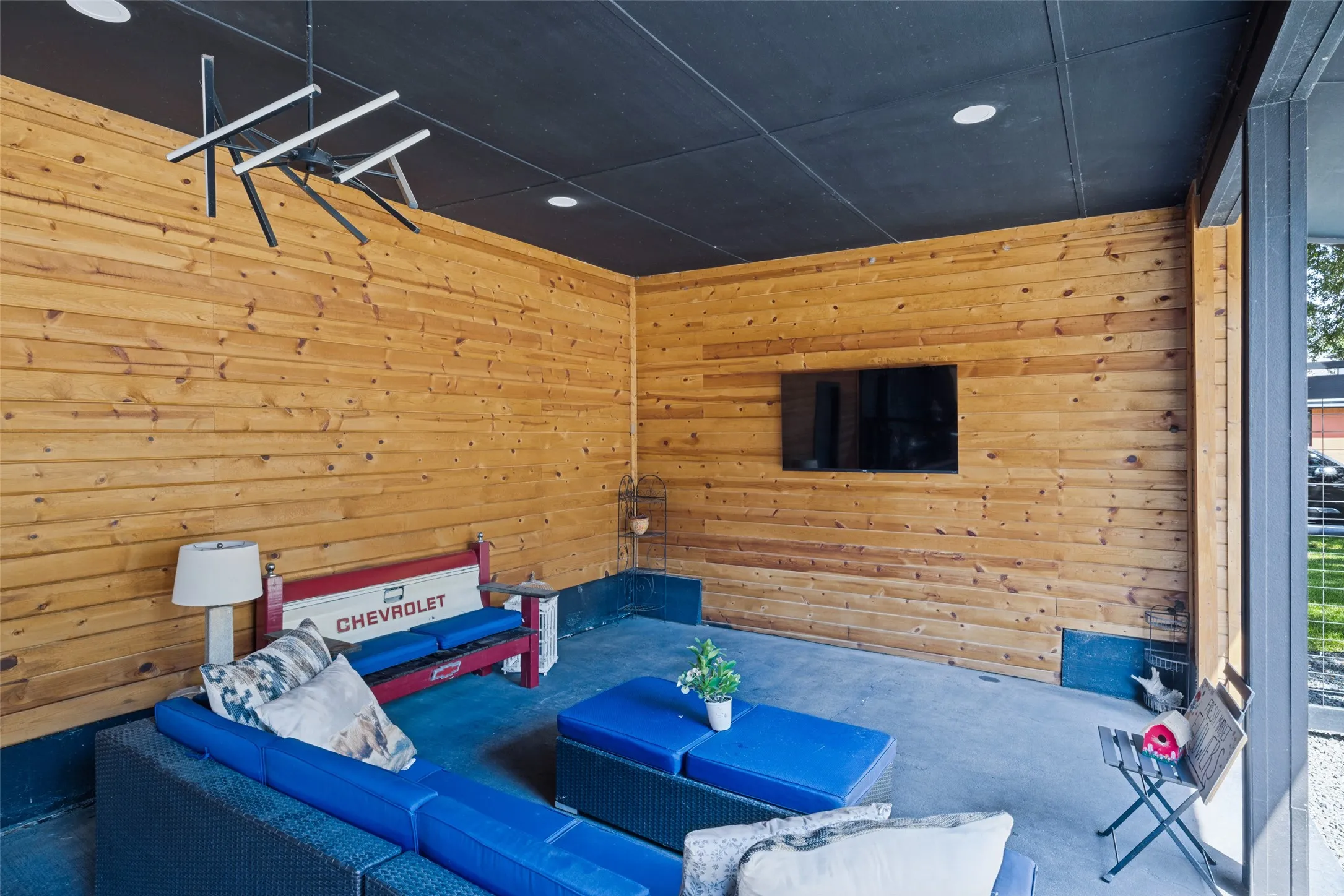 Covered patio featuring wood-paneled walls, a black ceiling, recessed lighting, and a modern chandelier