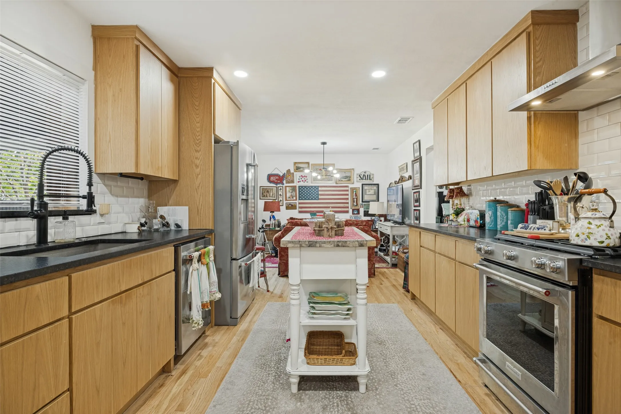 Well-appointed kitchen featuring wood-finish cabinetry, dark countertops, and a subway tile backsplash