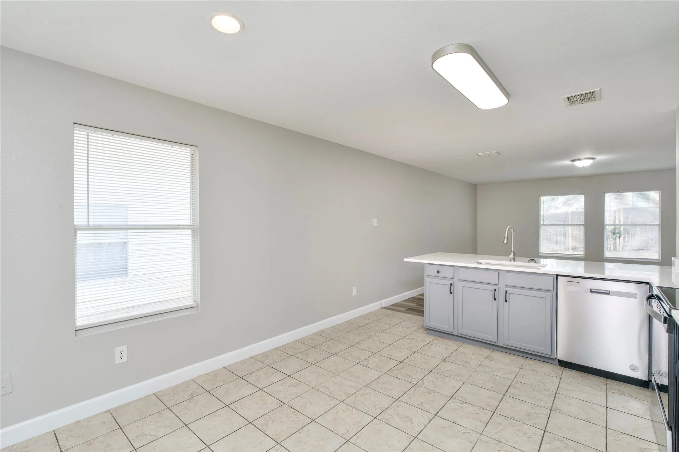 Kitchen with a center island, stainless steel appliances, light gray cabinetry, white countertops, and tile flooring