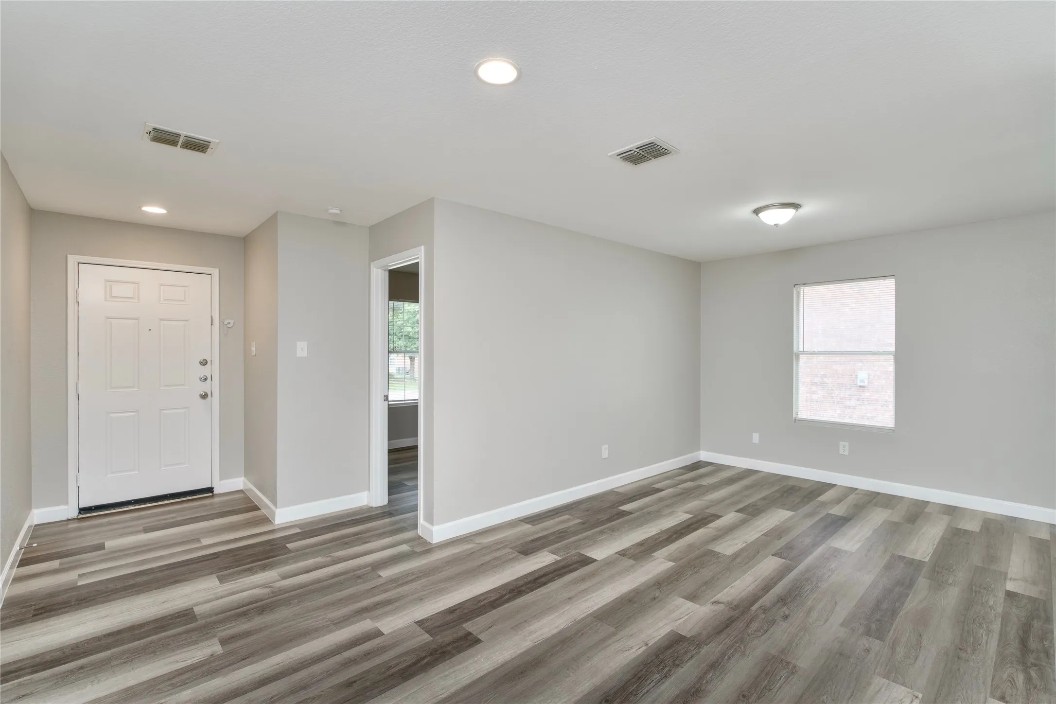 Wood-finish flooring, recessed lighting, and a white paneled entry door