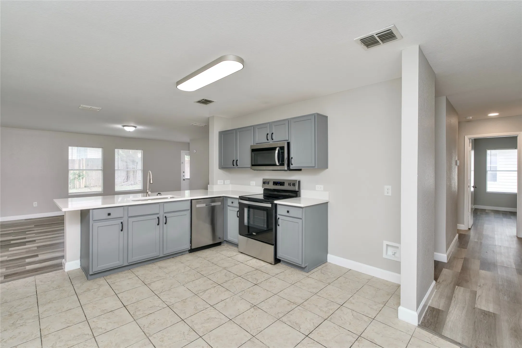 Kitchen featuring grey cabinetry, stainless steel appliances, a white countertop, and tile flooring