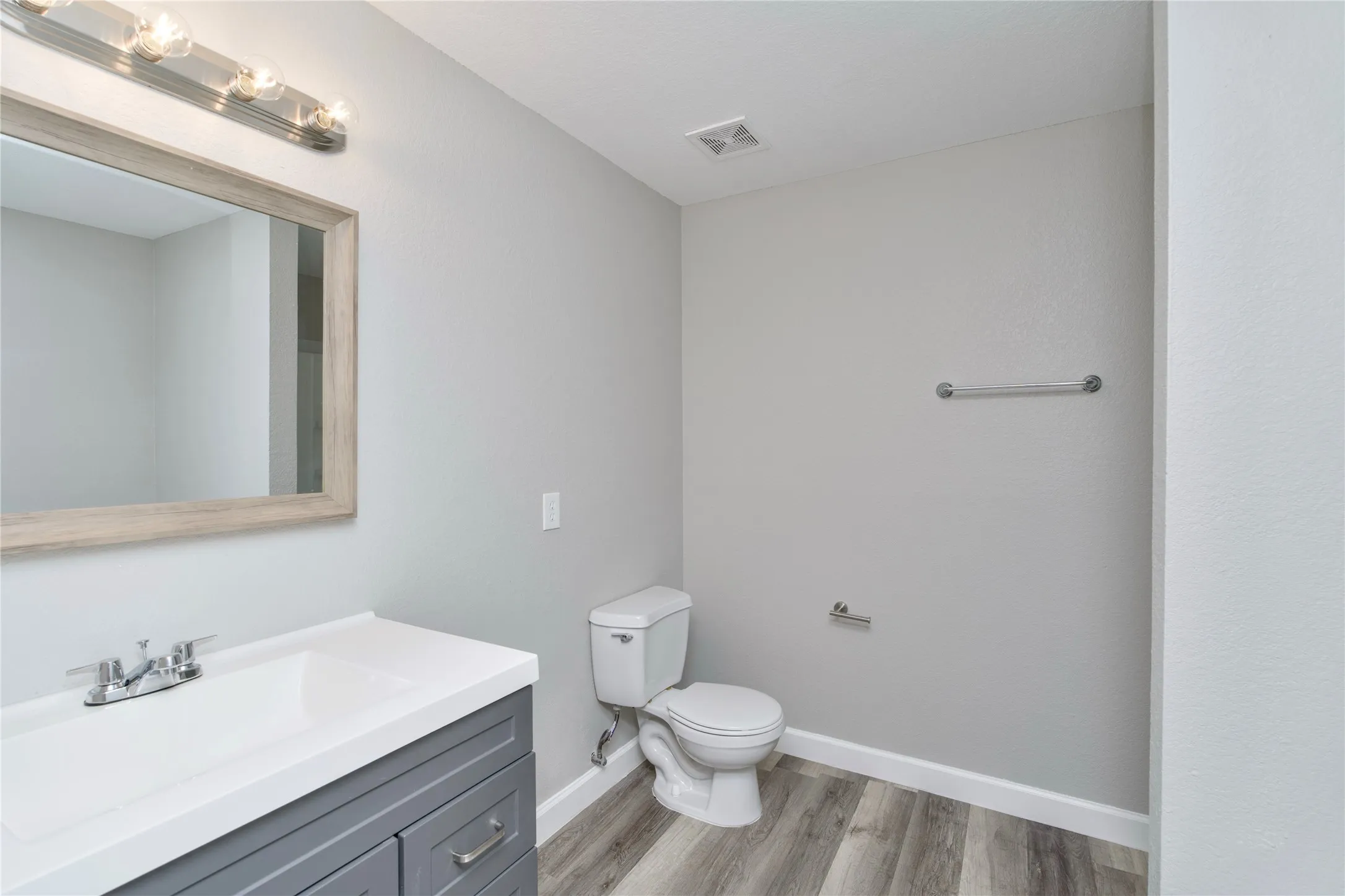 White vanity with integrated sink, chrome faucet, and framed mirror