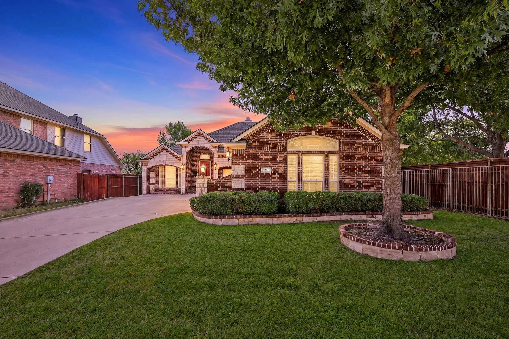 Brick exterior with stone accents, arched windows, covered entry, and a paved driveway