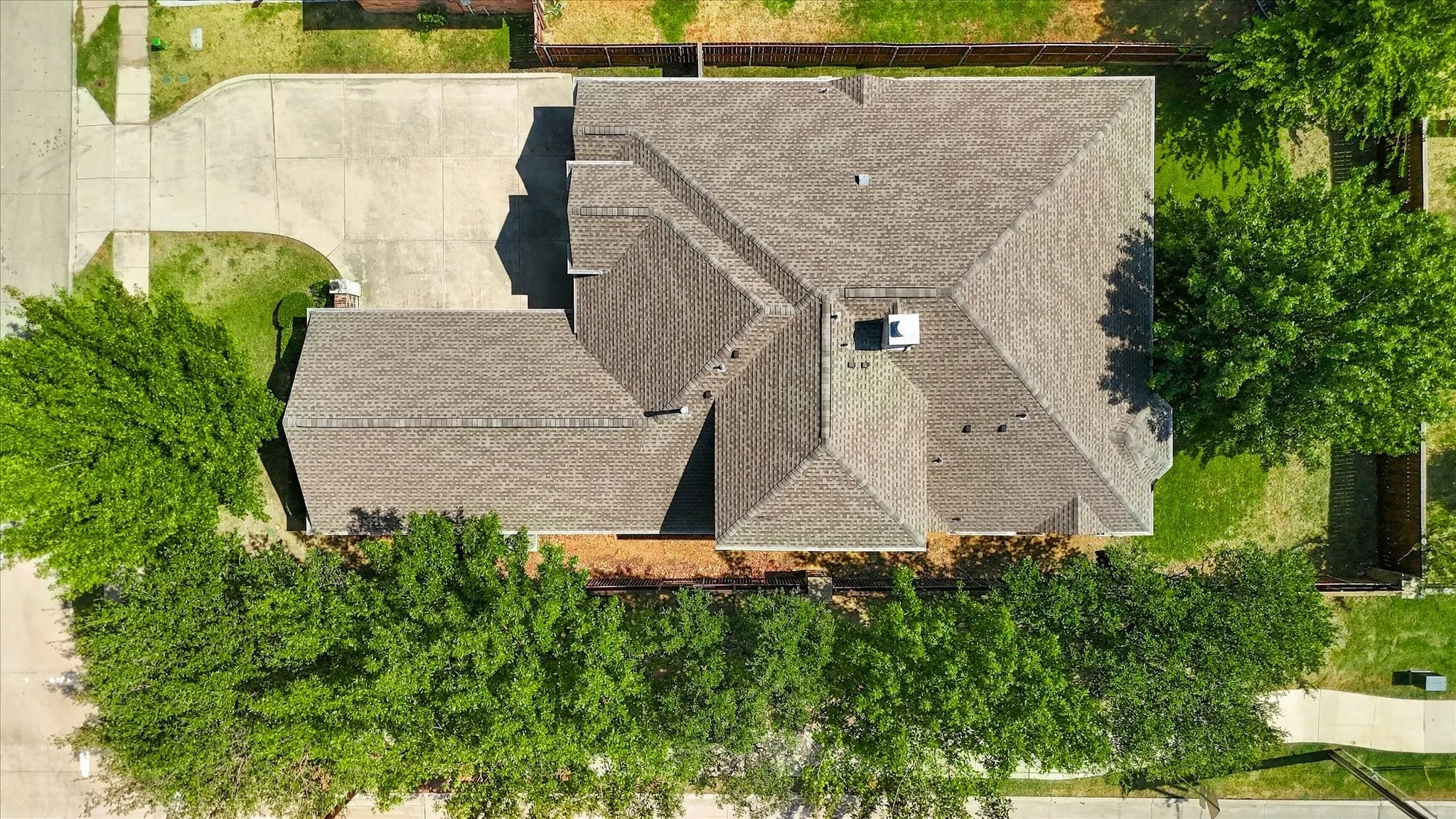 Expansive property featuring a multi-gabled roofline, concrete driveway, and mature landscaping
