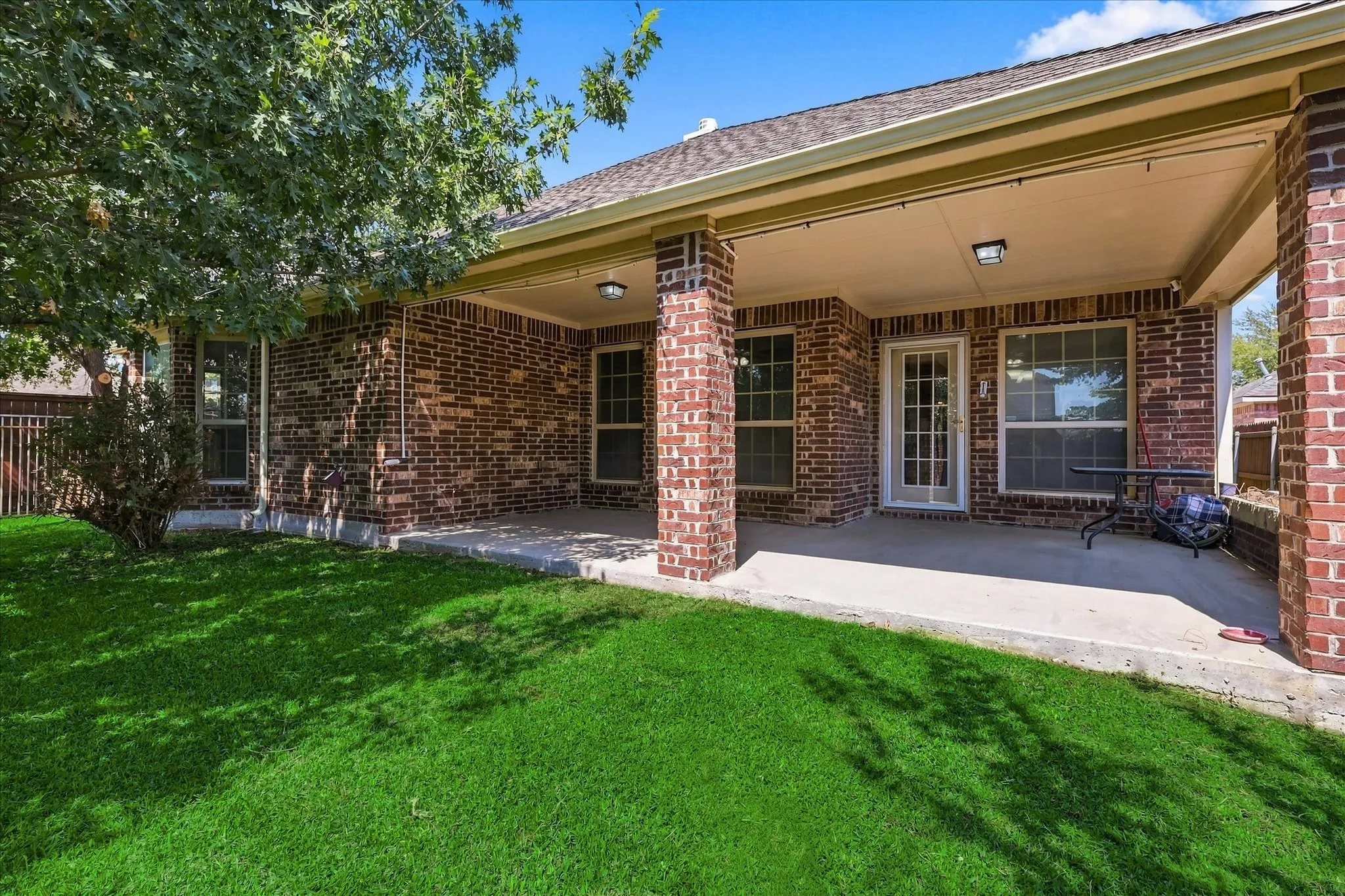 Expansive covered patio with brick columns and recessed lighting