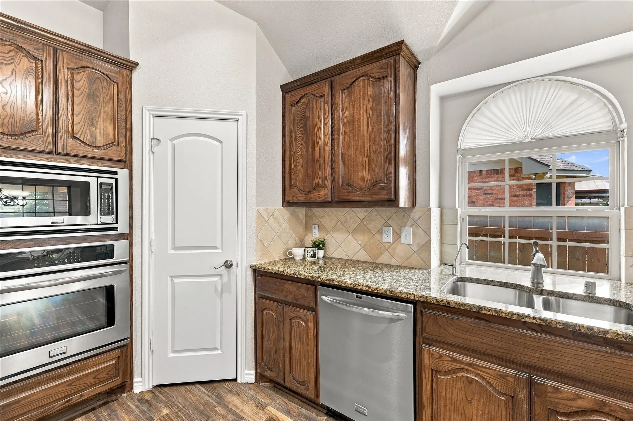 Wood-finish flooring, wood cabinetry, stainless steel appliances, granite countertops, and tile backsplash