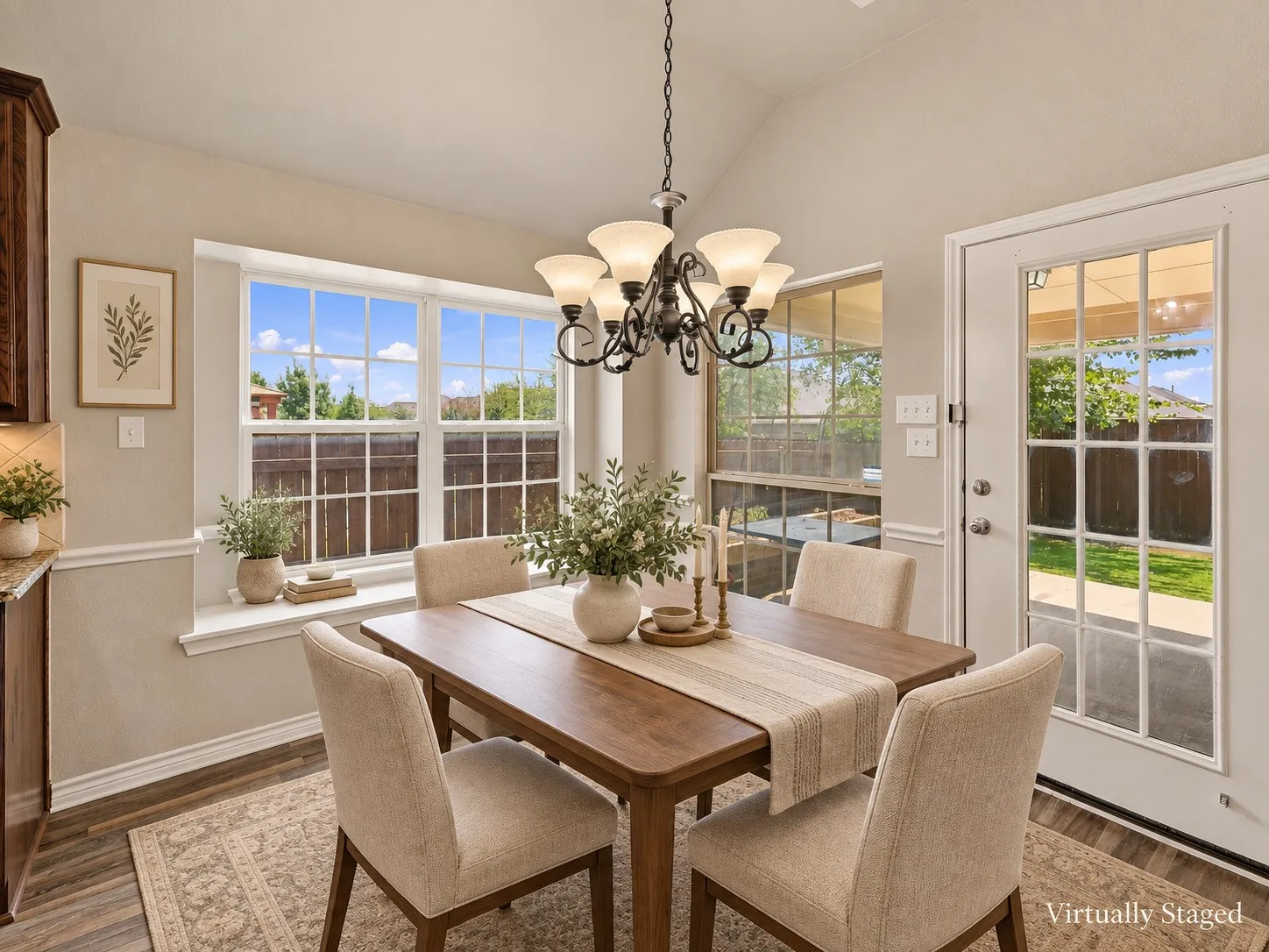 Vaulted ceiling featuring a chandelier, wood-finish flooring, bay window, and a glass-paneled door