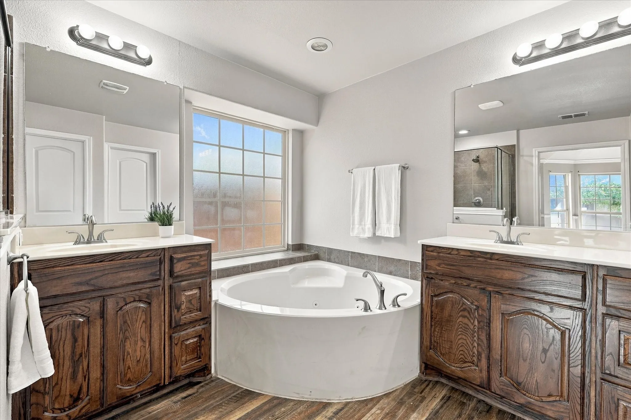 Dual wood-finish vanities with undermount sinks and light-toned countertops