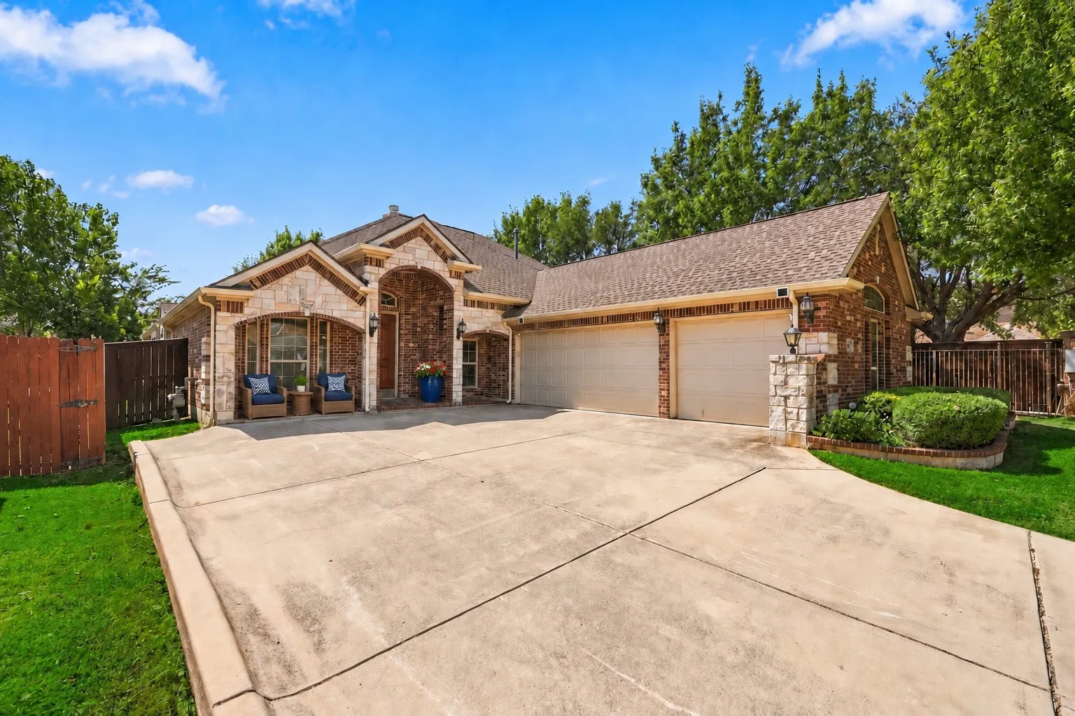 Brick and stone exterior with arched entryway, covered front porch, and an attached two-car garage