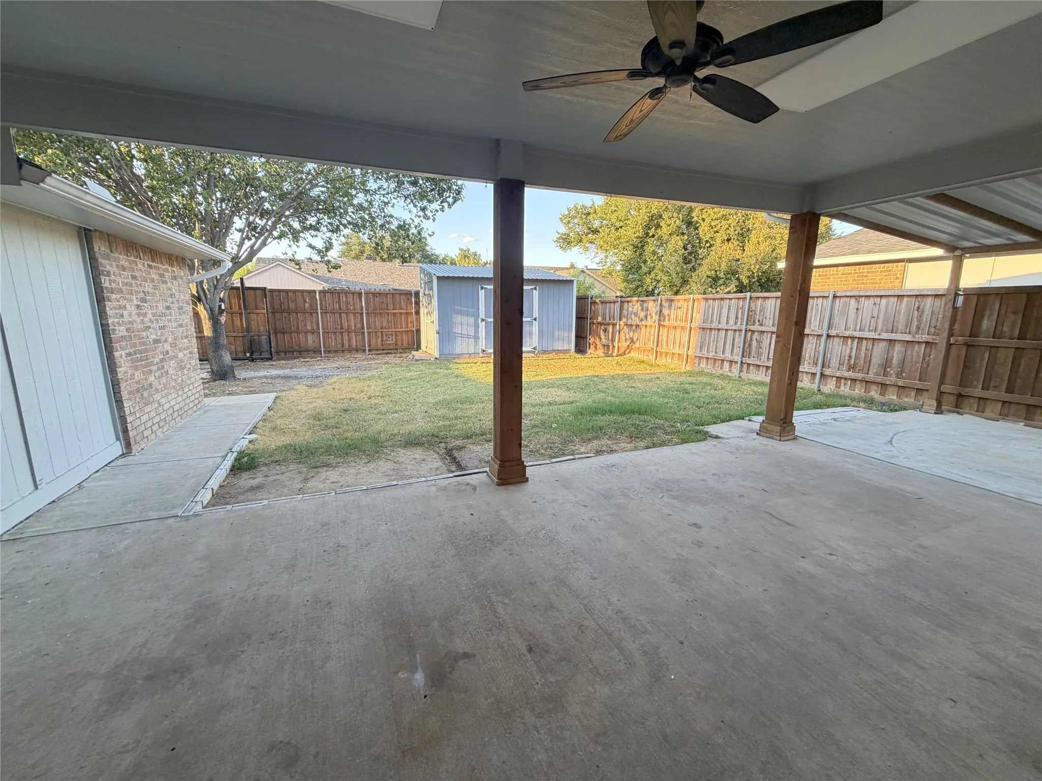 Covered patio with an attached ceiling fan, concrete flooring, and wooden support columns