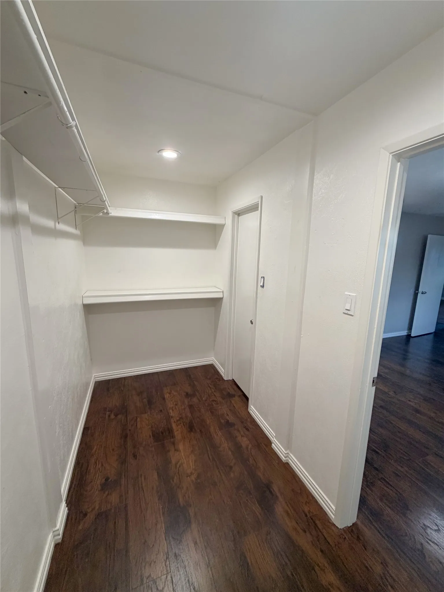 Built-in shelving, dark wood-finish flooring, recessed lighting, and white trim