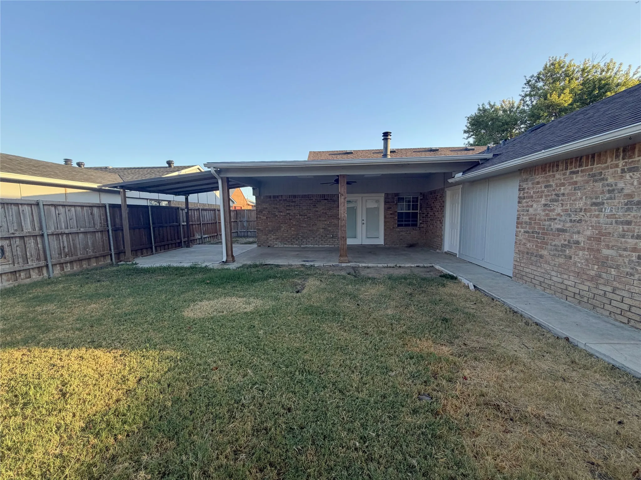 Brick exterior with covered patio, concrete walkway, and private fenced yard